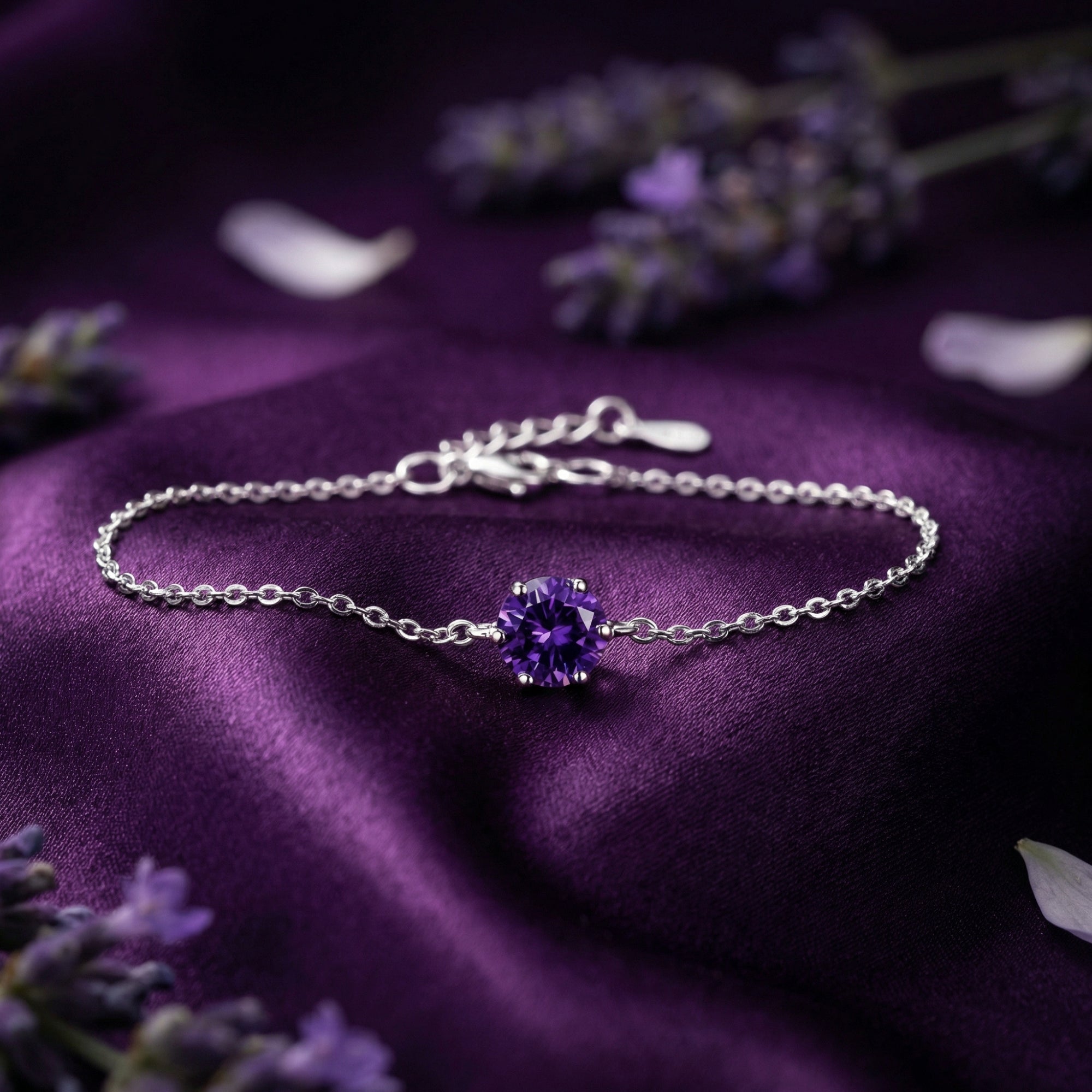 Close-up of a sterling silver amethyst solitaire bracelet resting on draped purple silk with lavender flowers.