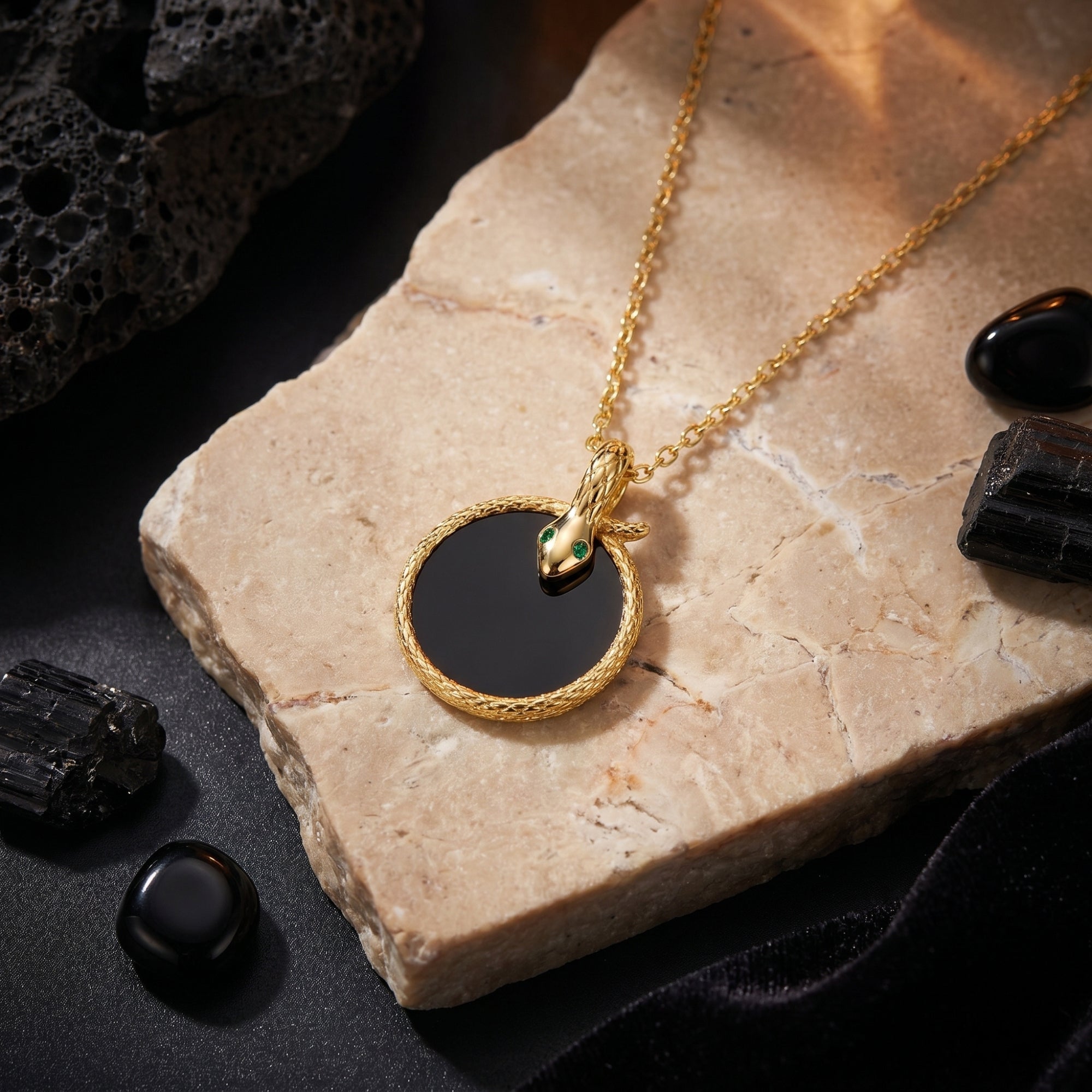 Macro shot of the gold snake pendant with green eyes and round black onyx stone.
