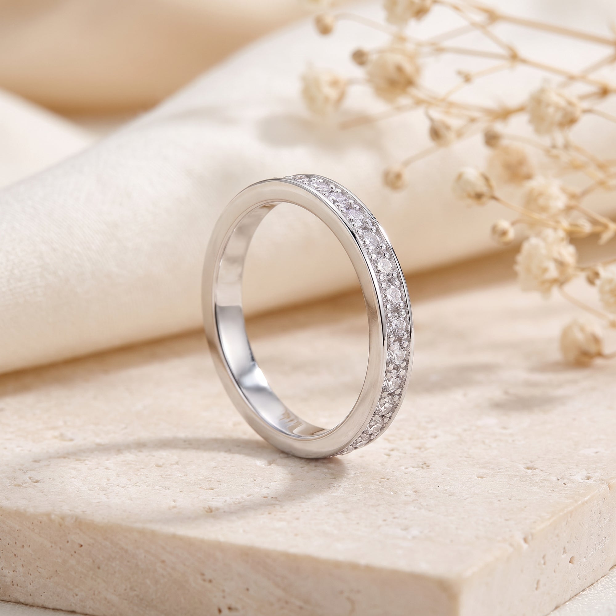 Side view of silver eternity ring with cubic zirconia on stone background.