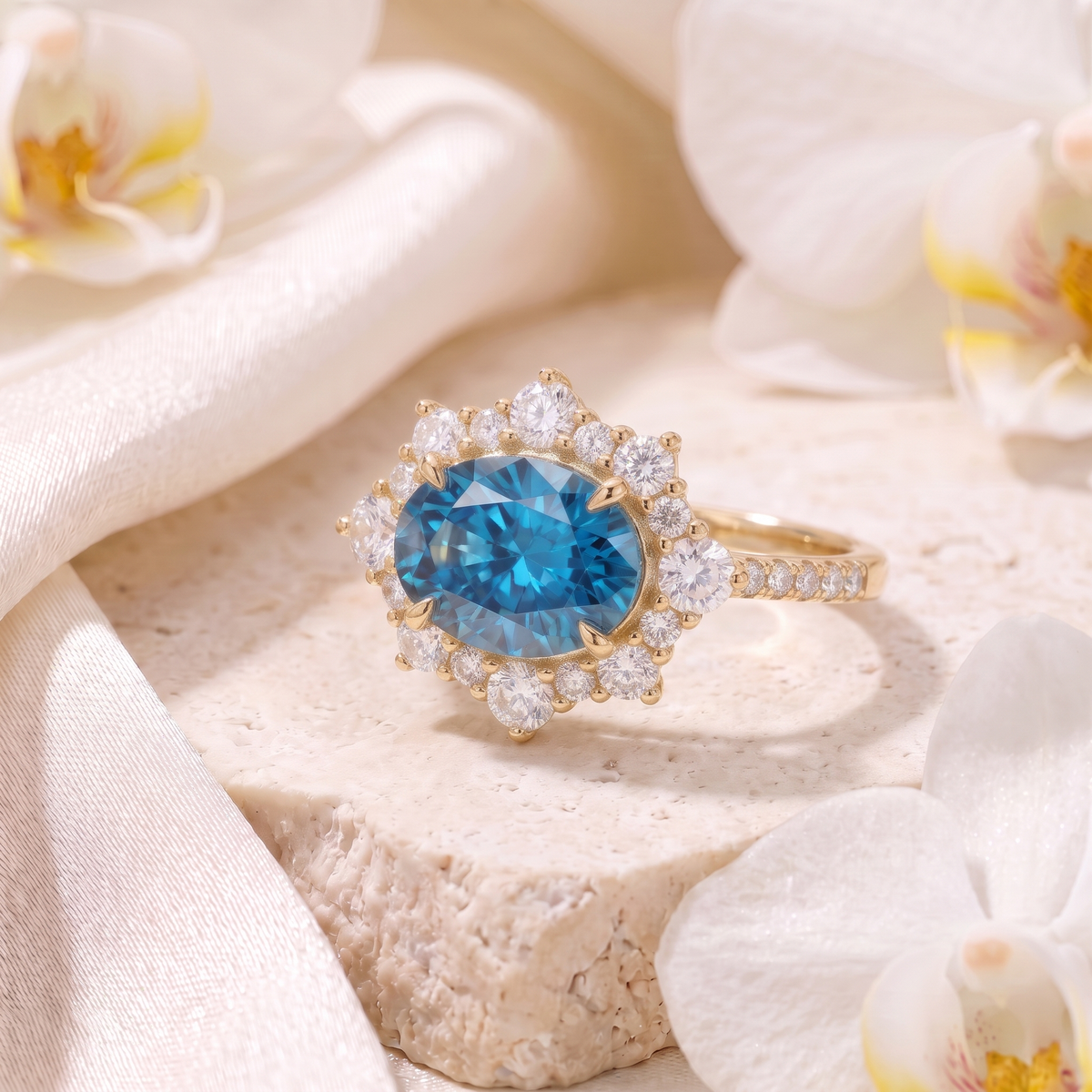 Angled view of a yellow gold oval blue moissanite halo ring resting on stone surrounded by orchids.