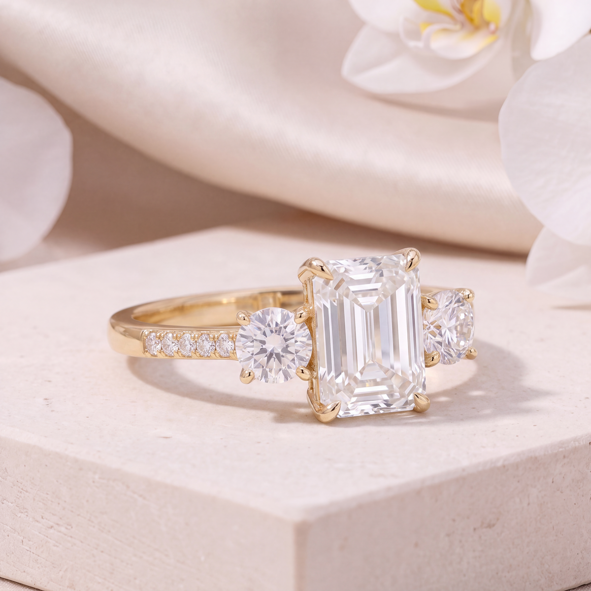 Angled view of a yellow gold emerald cut moissanite three-stone ring displaying side detail.