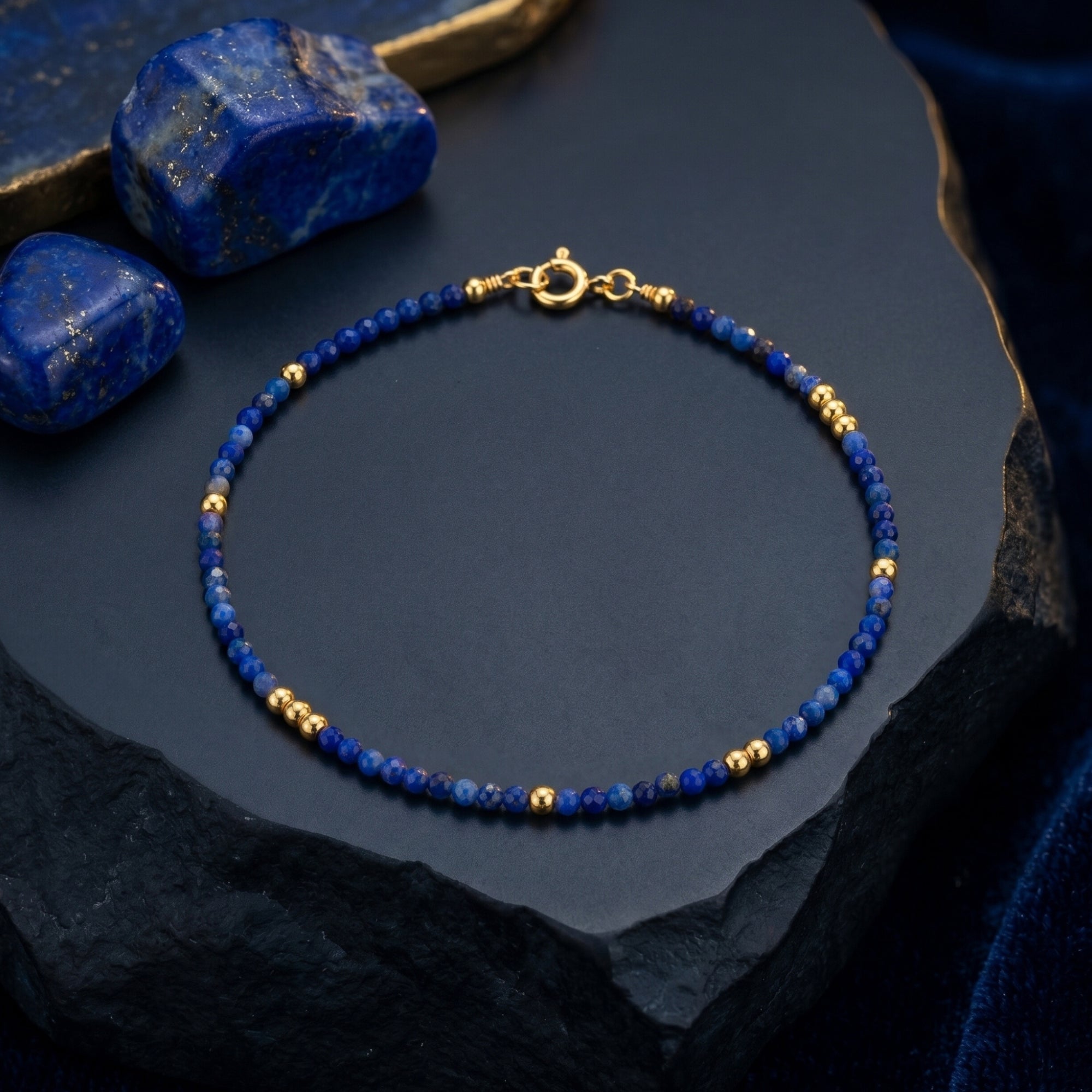 Top down view of the Celestial Dawn lapis lazuli bracelet with gold beads on a dark textured stone.