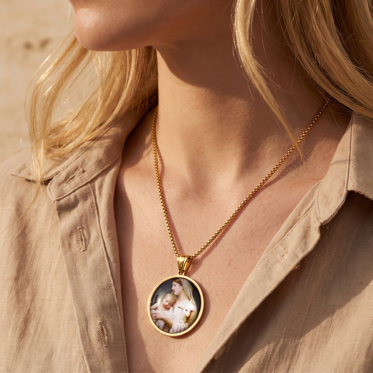 Woman wearing the gold-tone round Madonna and Child medallion necklace with a beige collared shirt.
