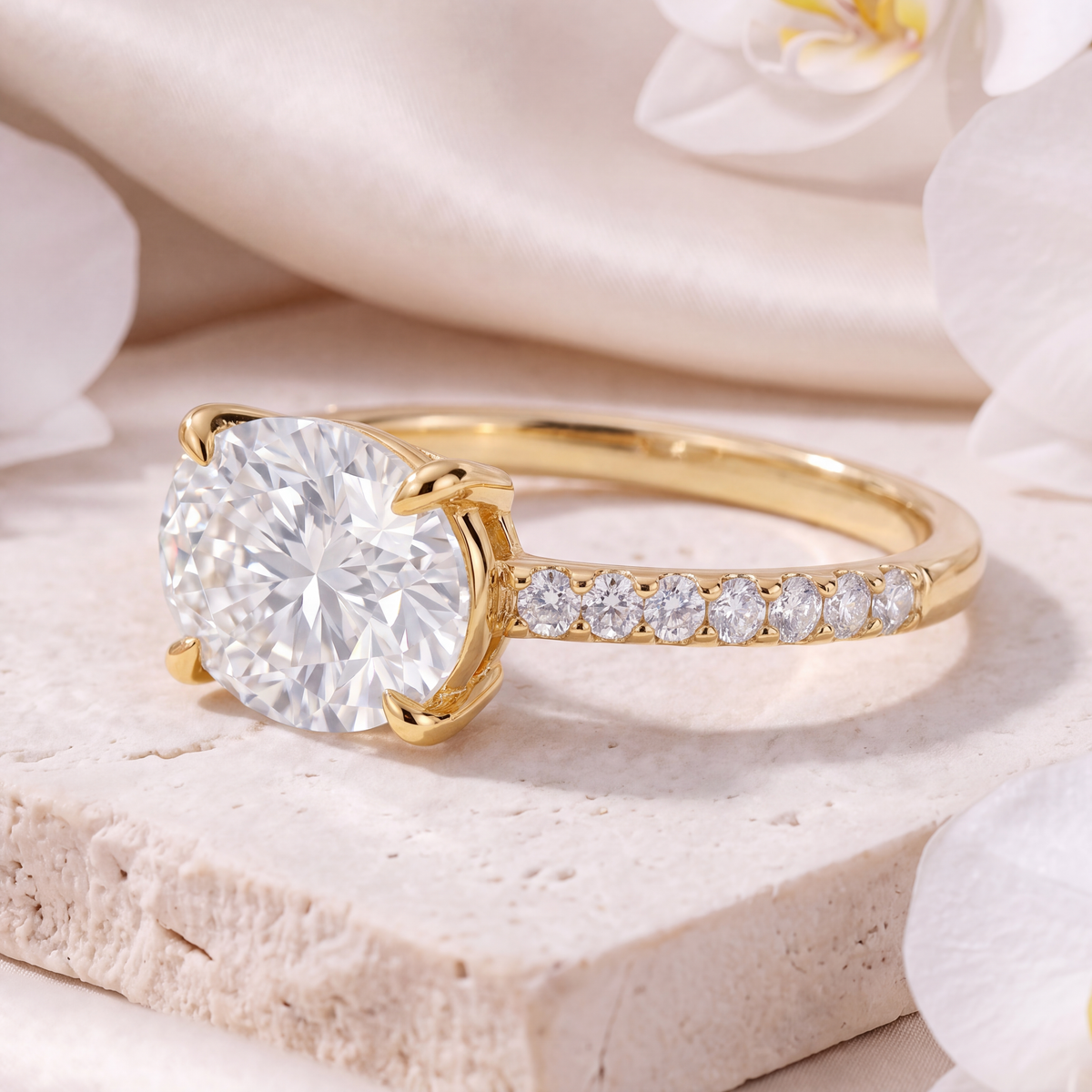 Side view of an east-west oval moissanite yellow gold engagement ring with a pavé accent band.