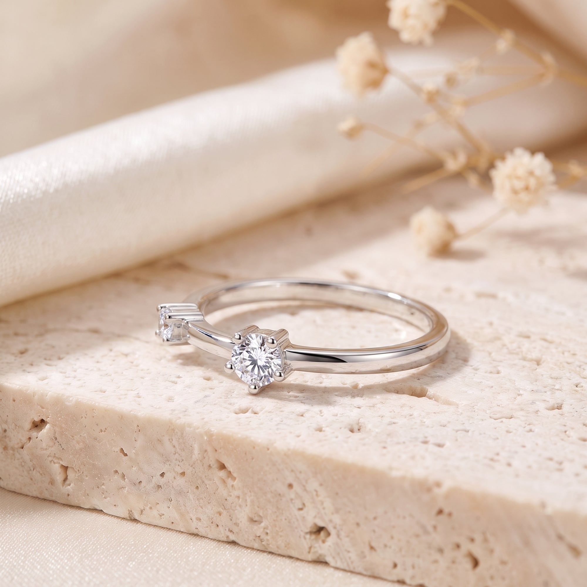 Close-up of round-cut simulated diamonds on a silver asymmetric bypass ring setting.