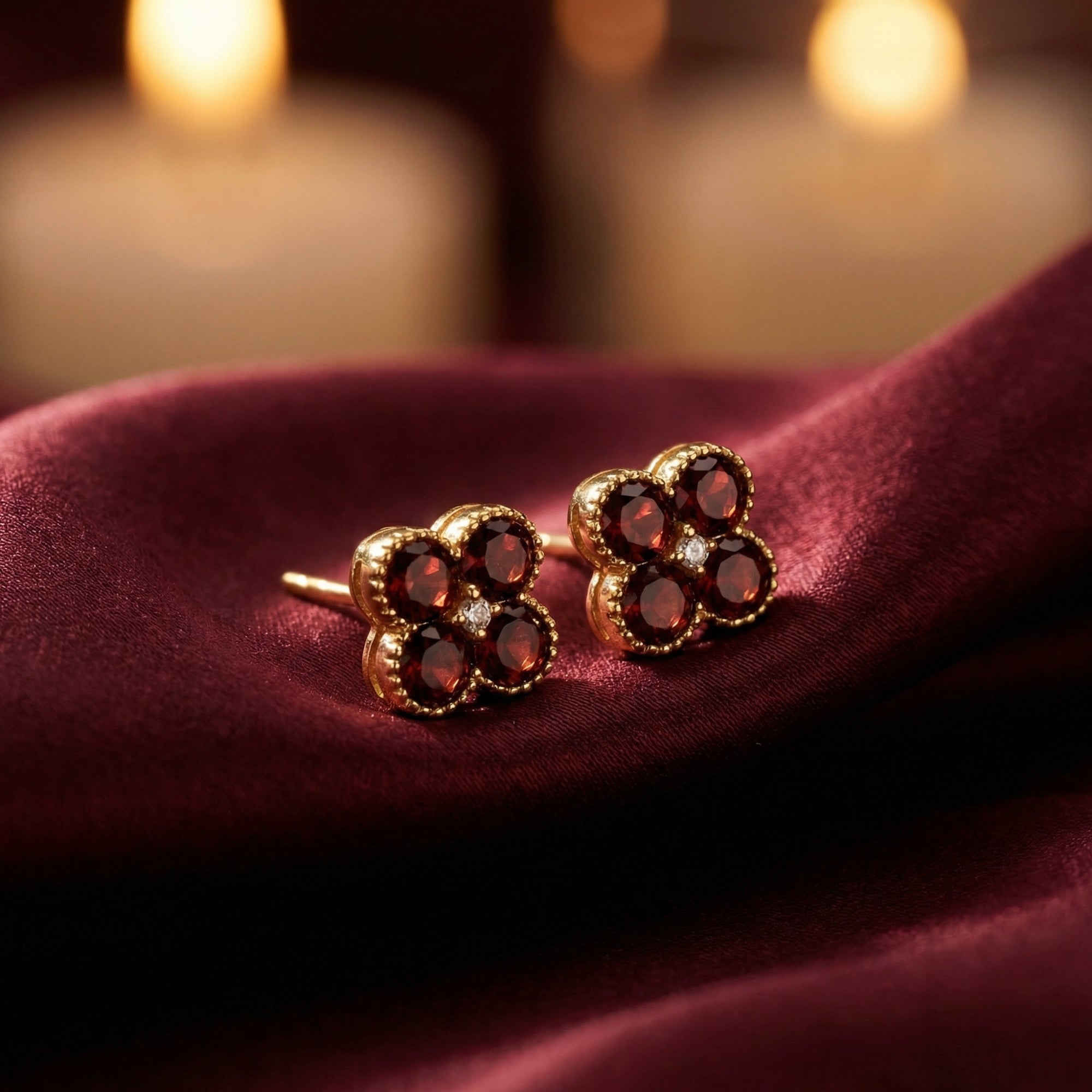 Close-up of Ambrosia floral studs in 18K yellow gold with round red garnets and center lab-grown diamonds.