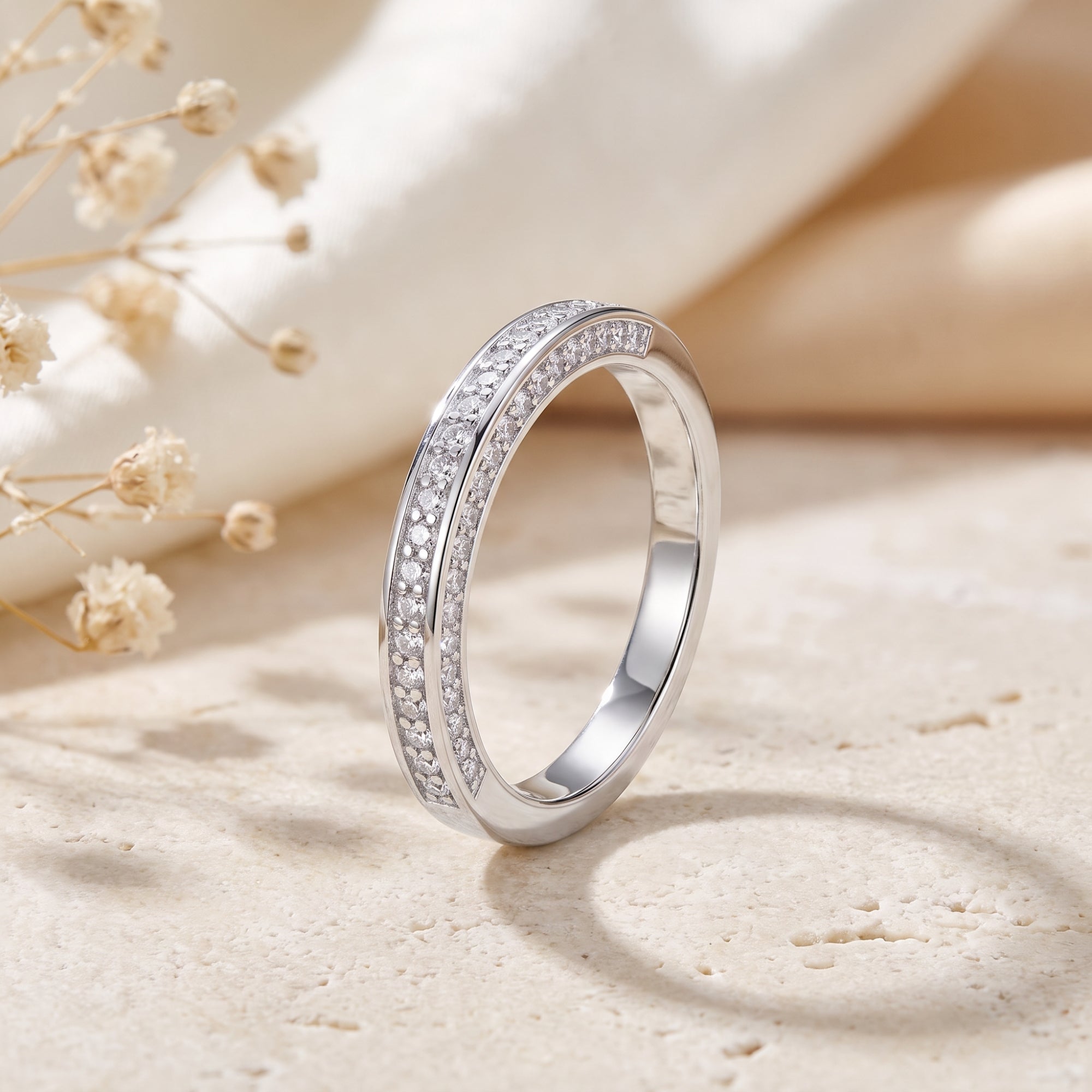 Side profile of a sterling silver double row pavé band on a stone surface.