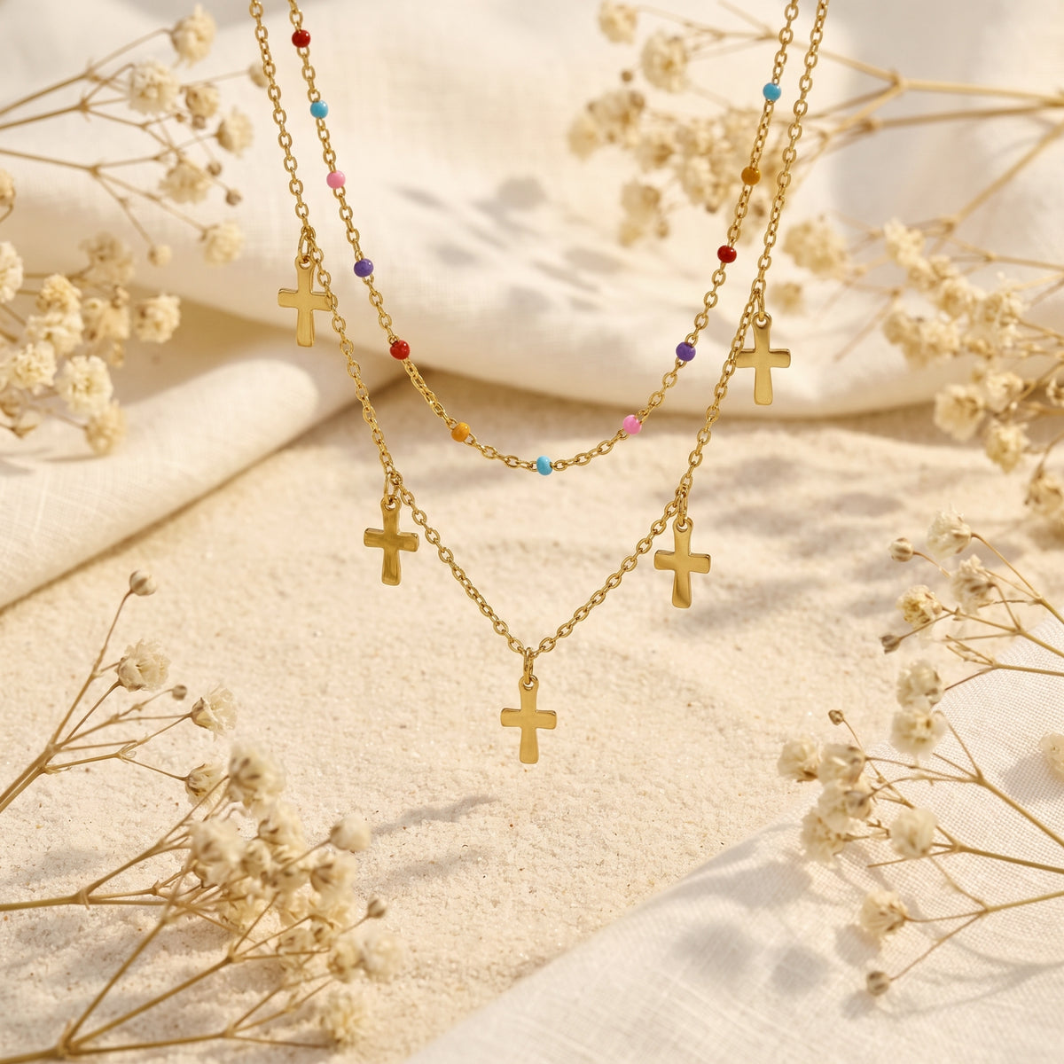 Suspended close-up of the double-layer gold-tone necklace showing colorful beads and small cross charms.