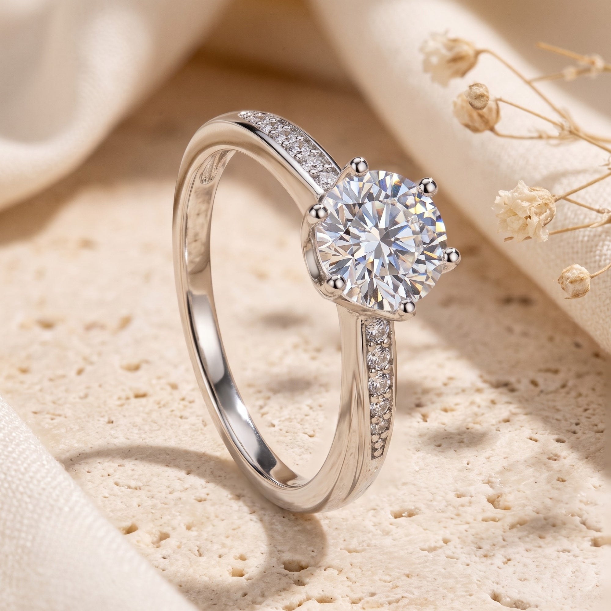 Close-up of silver solitaire ring showing six-prong setting and pavé band.