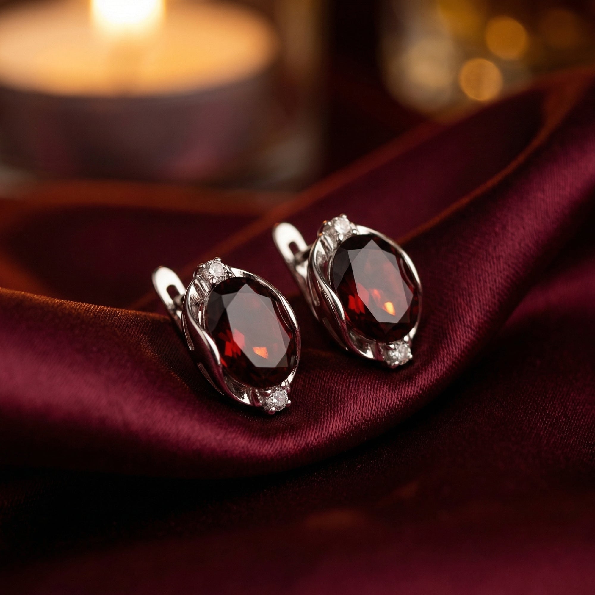 Detailed view of the 8x10mm oval cut garnet drop earrings in sterling silver showing the faceted red gemstones.
