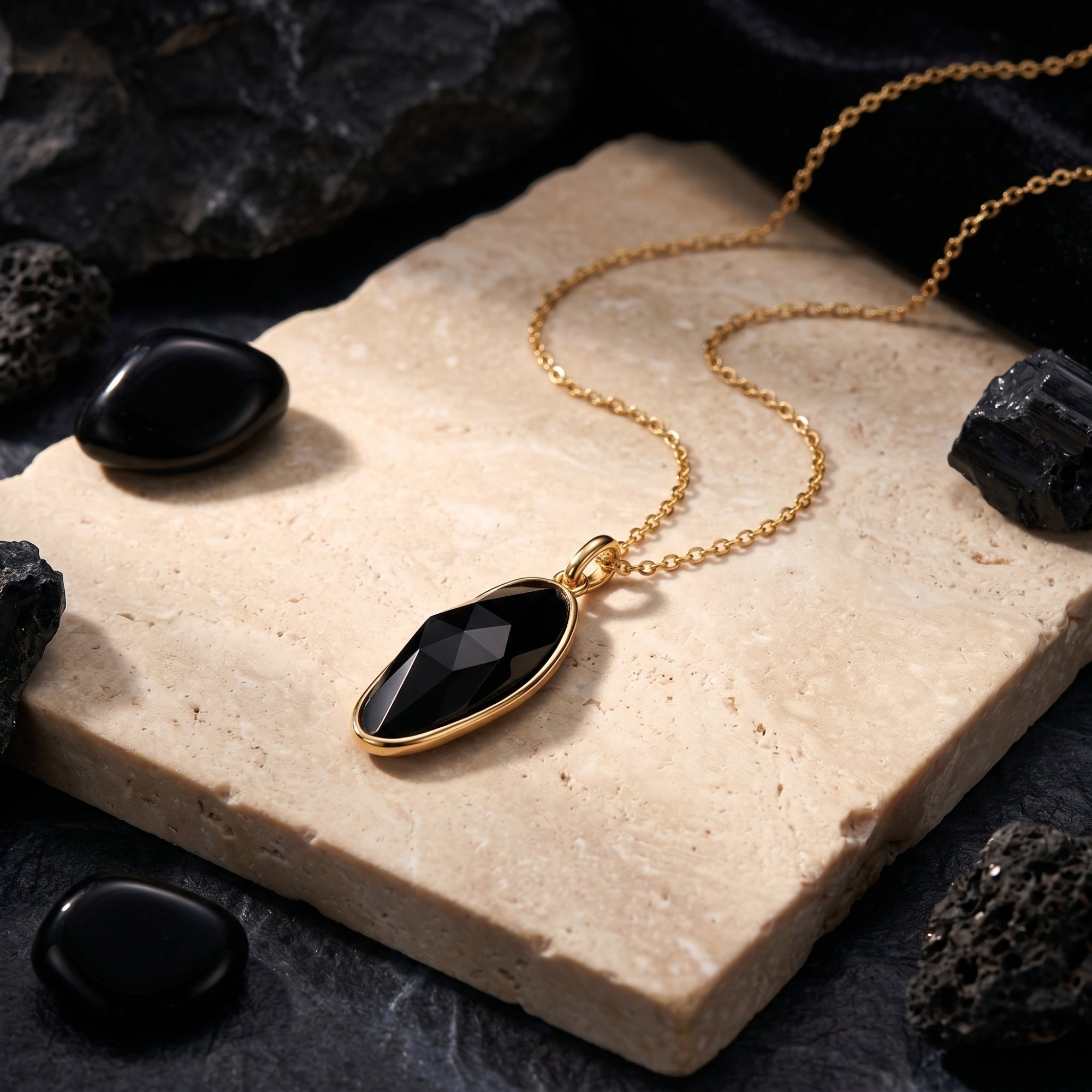 Close-up of the faceted irregular-cut natural black onyx pendant in a gold setting on a textured stone surface.