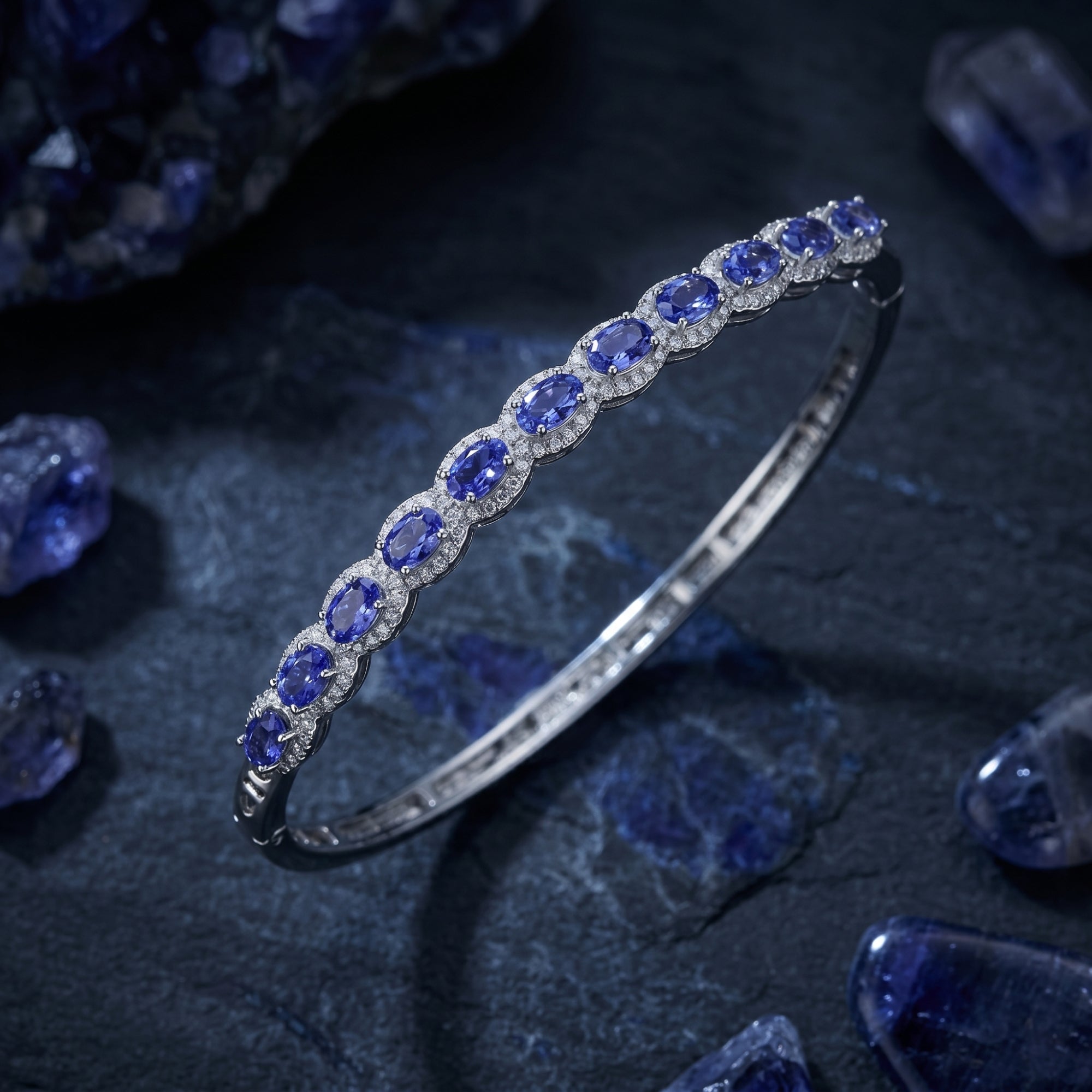Macro view of oval-cut natural tanzanite stones in a white gold halo setting on a dark textured surface.