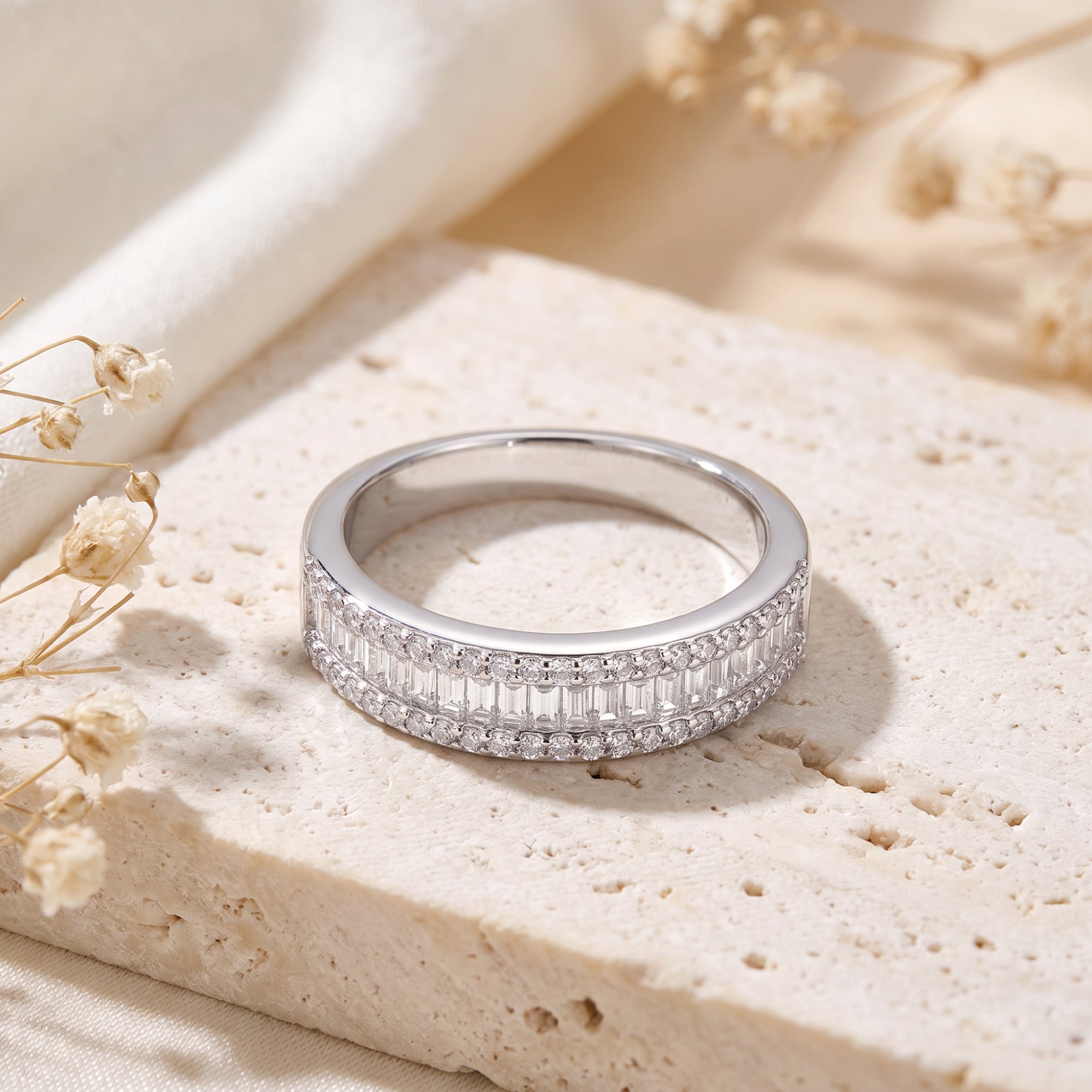 Top view of a sterling silver channel-set band with baguette and round cubic zirconia on a textured stone.