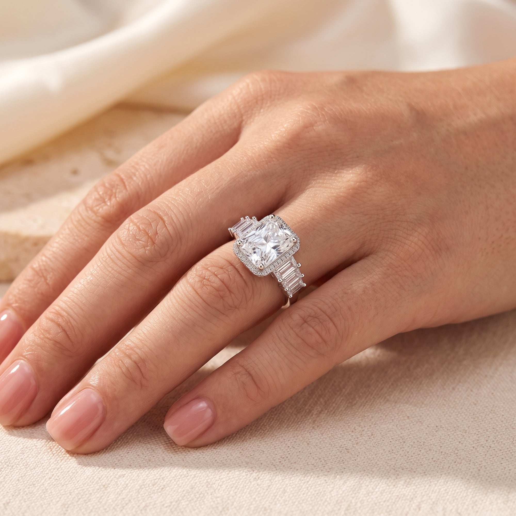 Cushion-cut simulated diamond halo ring in sterling silver shown on a finger for scale.