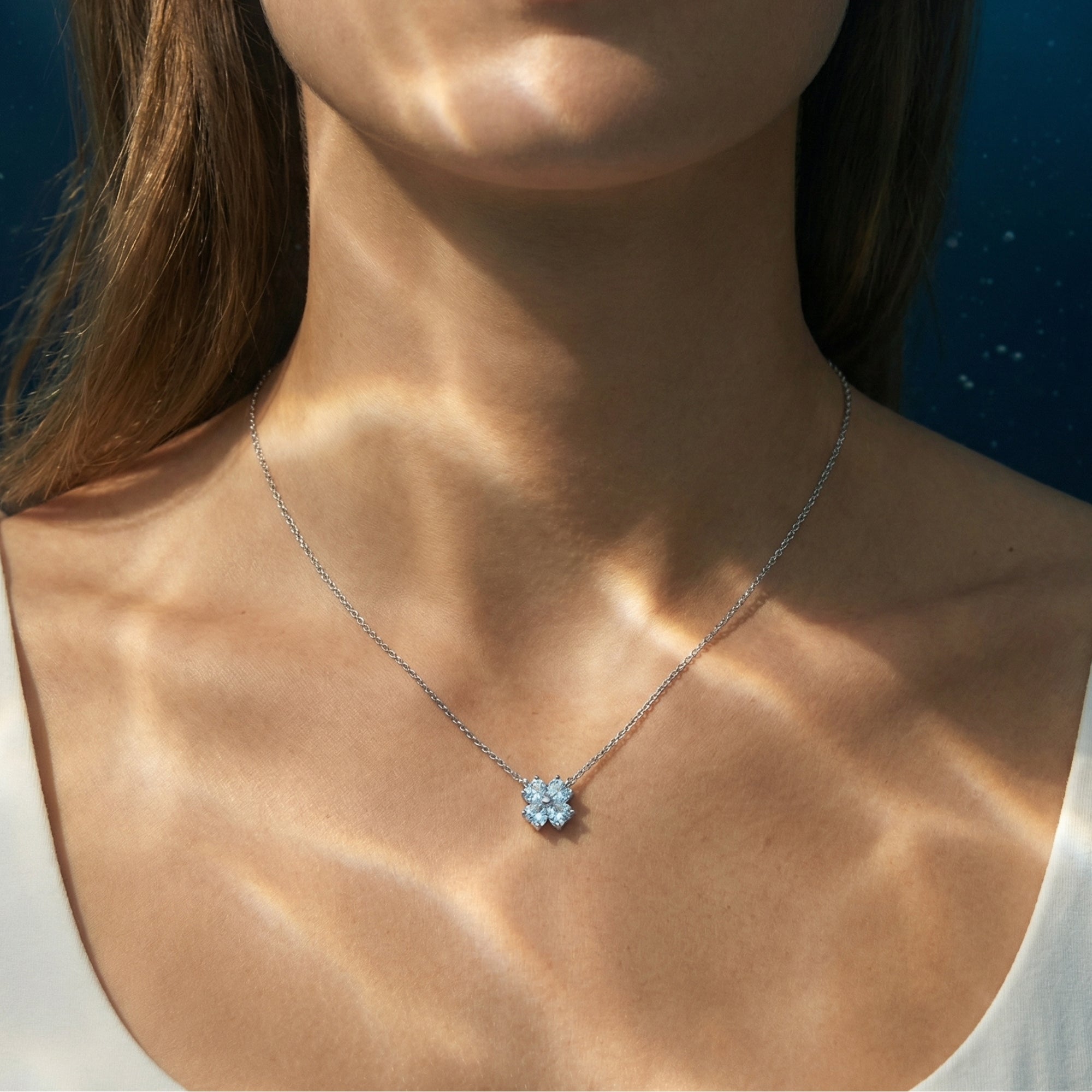 March birthstone heart-cut aquamarine clover pendant in platinum worn by a woman.