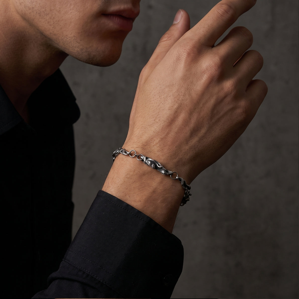 Side view of a man wearing the textured oxidized silver chain bracelet with a black shirt.