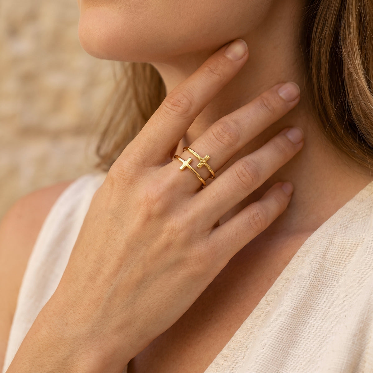 Model wearing the gold-tone double cross ring with her hand resting against her neck.