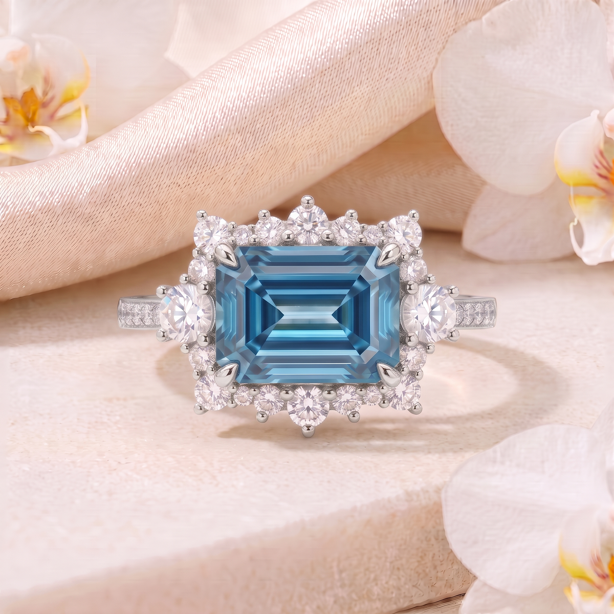 Front view of an emerald-cut blue moissanite halo ring in white gold on a stone surface.