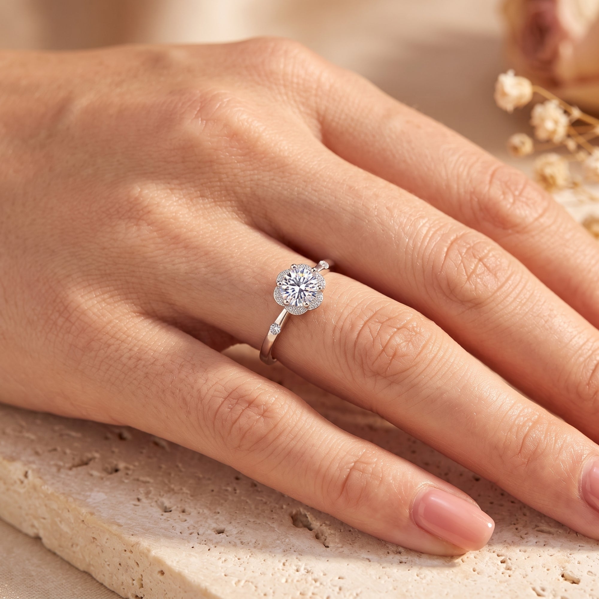 Sterling silver floral halo ring with round-cut stone on a model's finger.