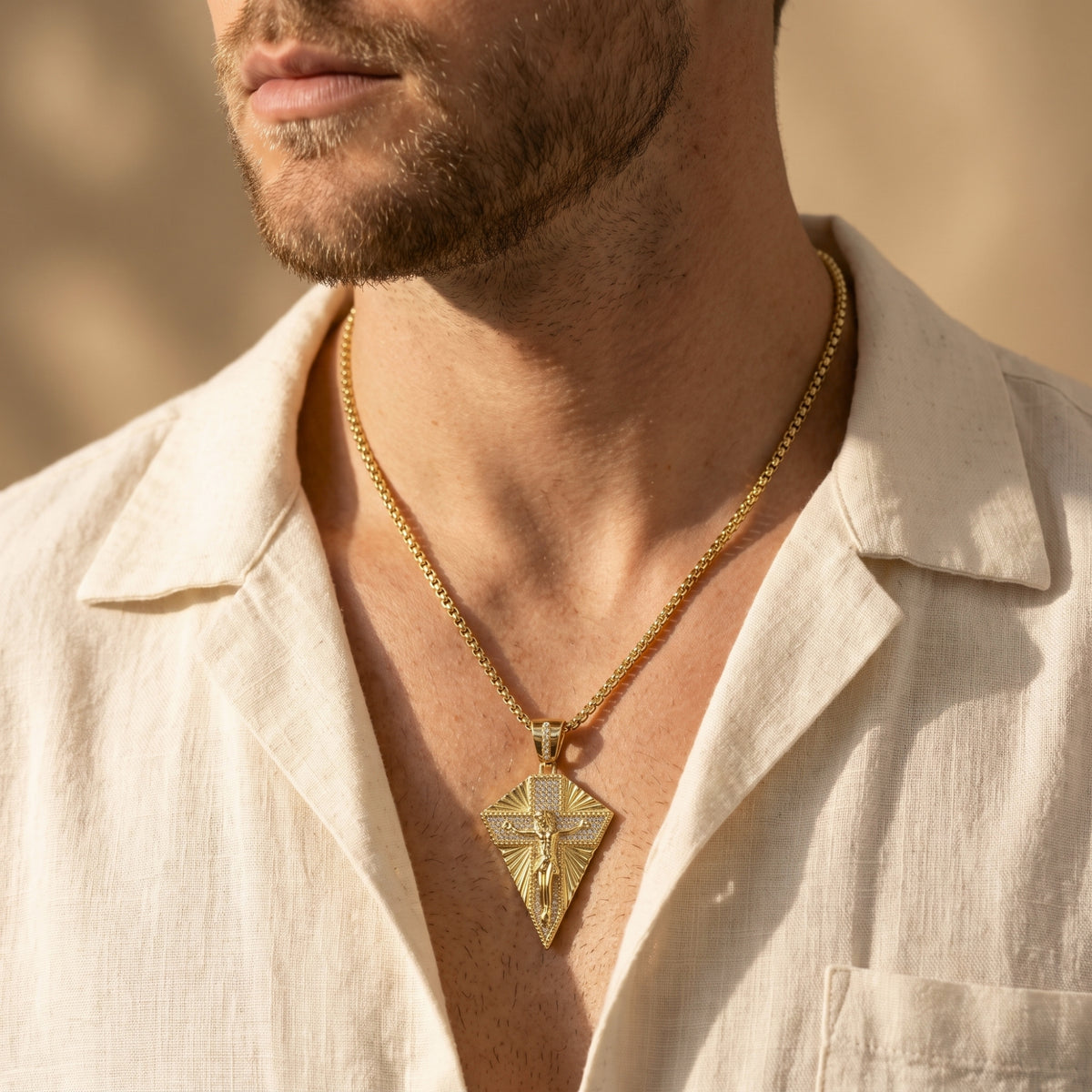 Angled close-up of a person wearing the gold-finished crucifix necklace over an open light-colored shirt.