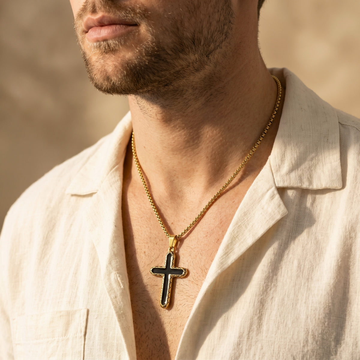 Model wearing the gold-tone black-inlay cross necklace over an open white shirt, shown in a front-facing close-up.