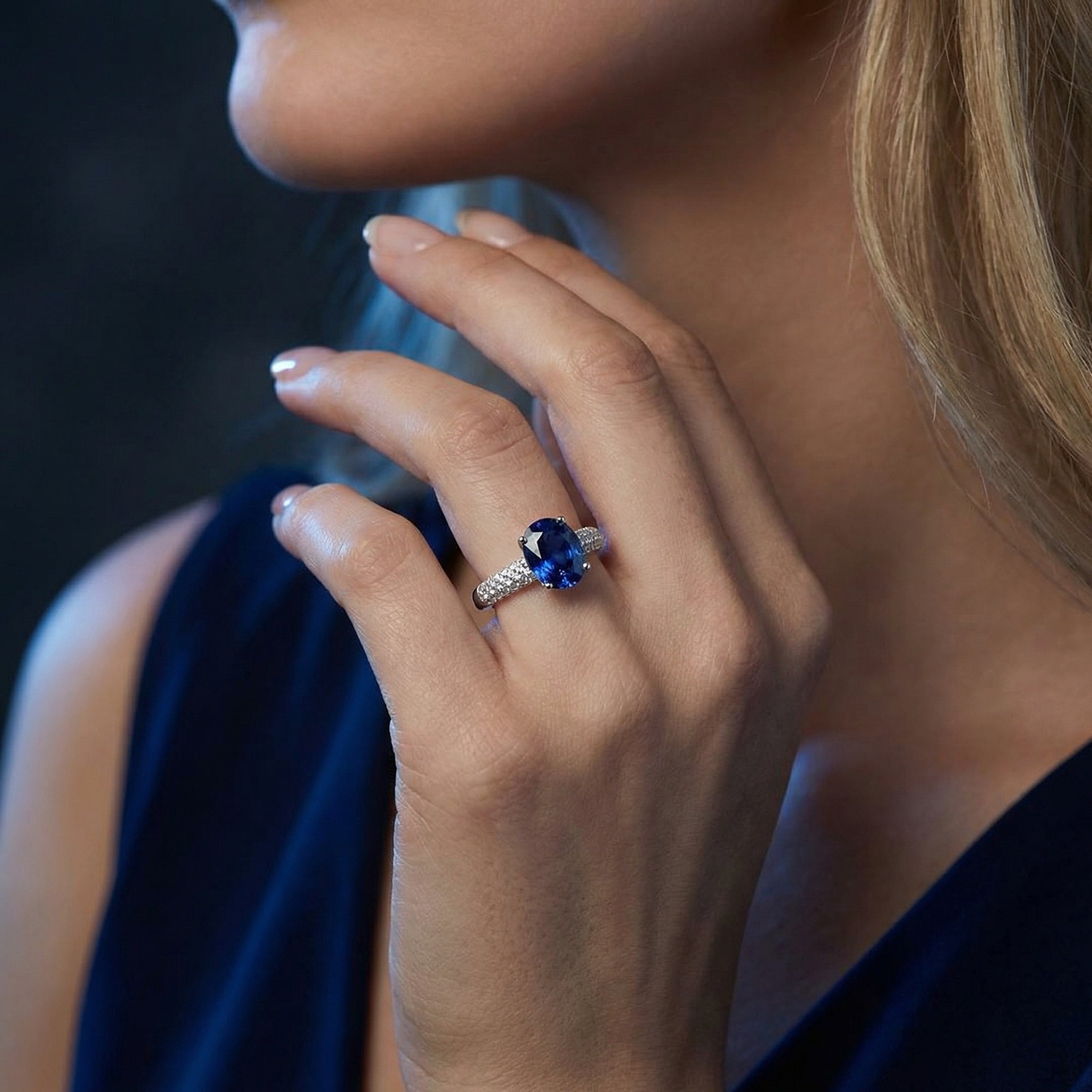 A woman wearing the Illyria oval tanzanite ring in sterling silver, showcasing the vibrant blue gemstone on her finger.