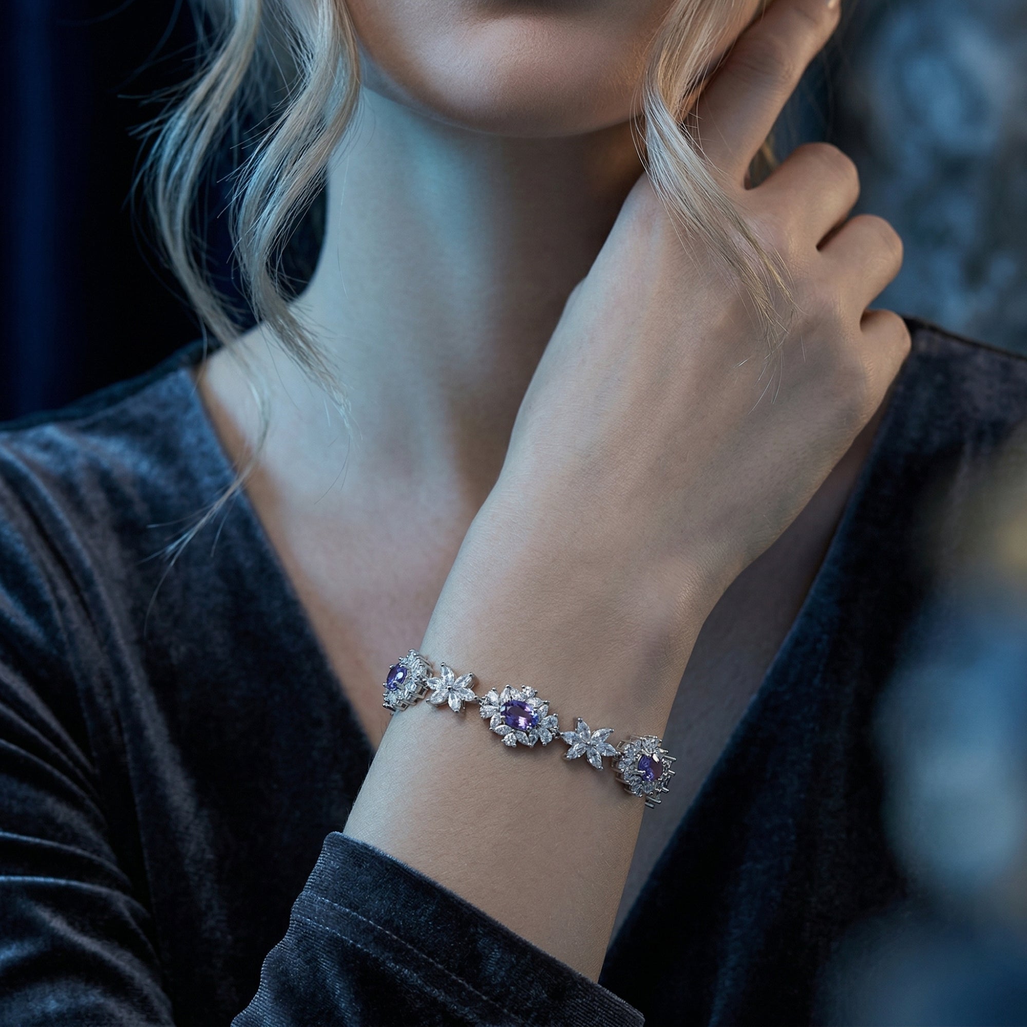 Woman wearing the Rosalira natural tanzanite floral bracelet in white gold with a dark dress.
