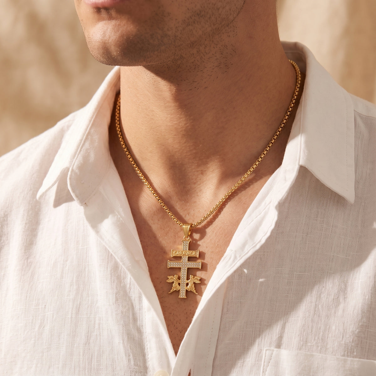 Gold Caravaca cross pendant necklace styled on a man wearing an unbuttoned white shirt.