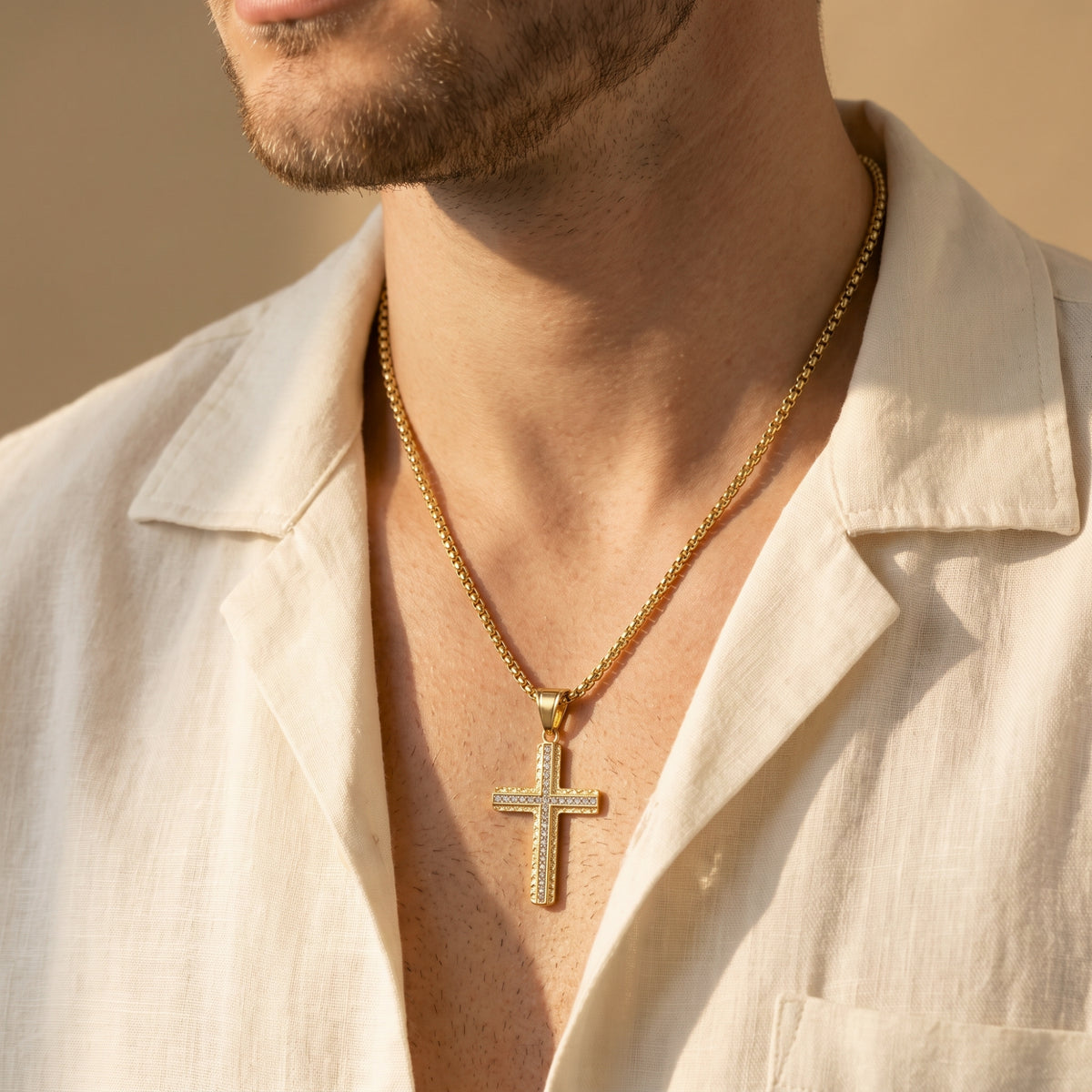Man wearing the gold-tone cross necklace with cubic zirconia accents, paired with an open cream shirt.