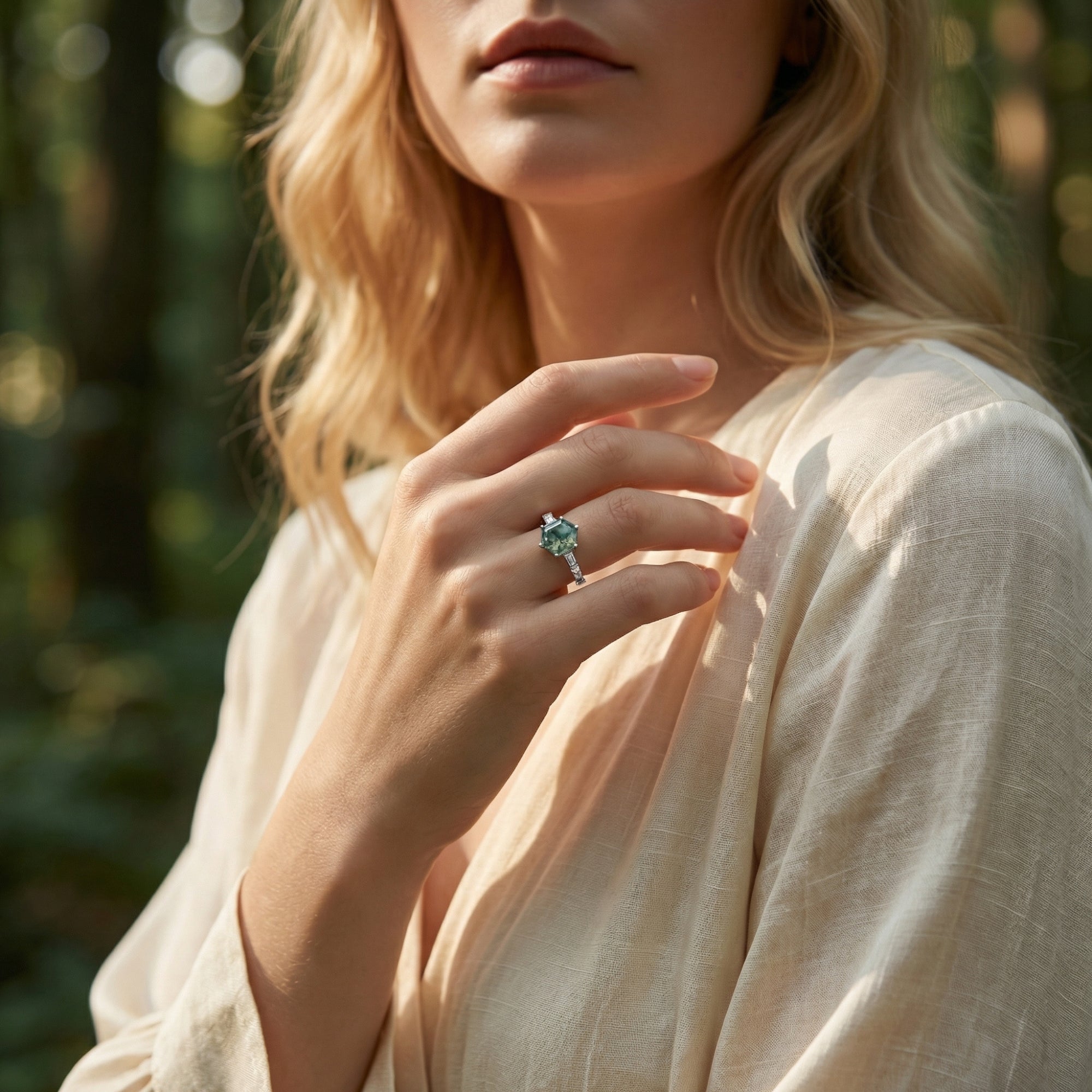 Lifestyle shot of a woman wearing a hexagonal moss agate sterling silver ring in a sunlit forest.