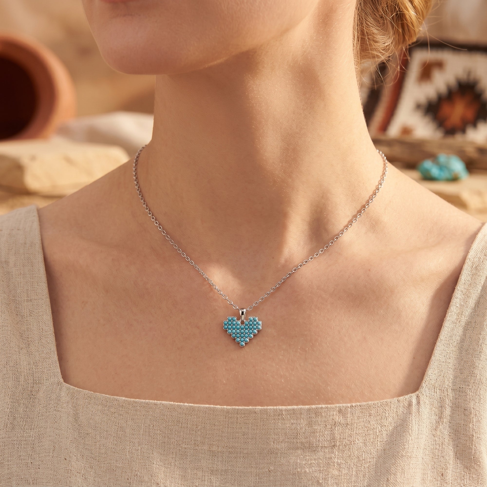 Model wearing a silver heart-shaped turquoise necklace, showcasing its length and Southwestern style.