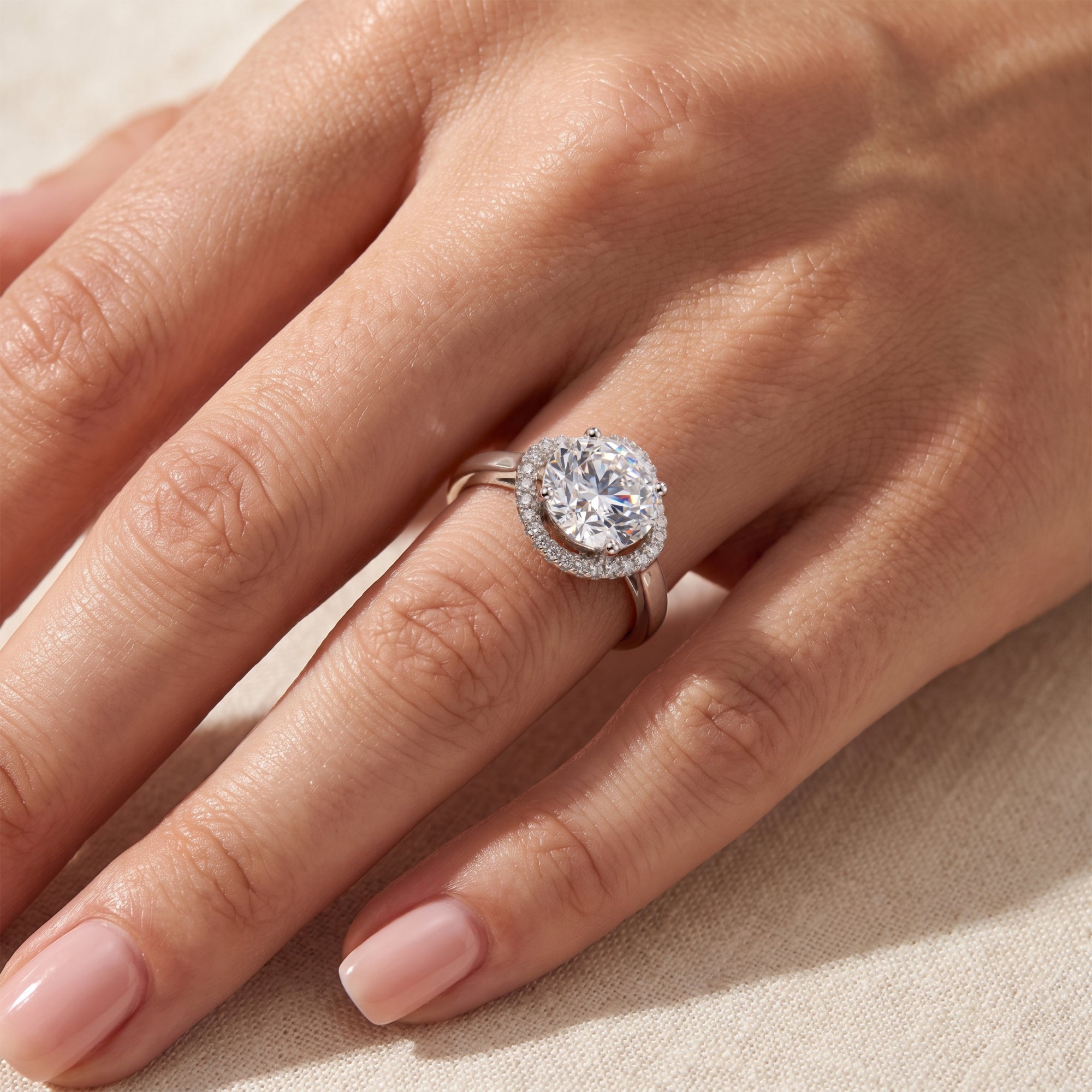 Top view of sterling silver round halo simulated diamond ring on a model's hand.