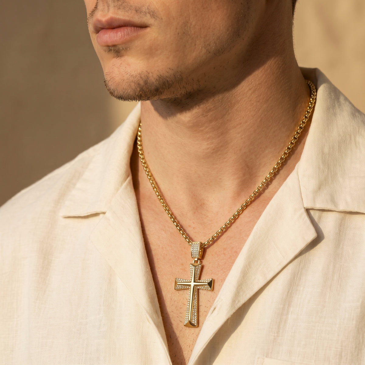 Close-up of a man wearing the gold-tone beveled cross necklace with pavé accents over an open-collar shirt.