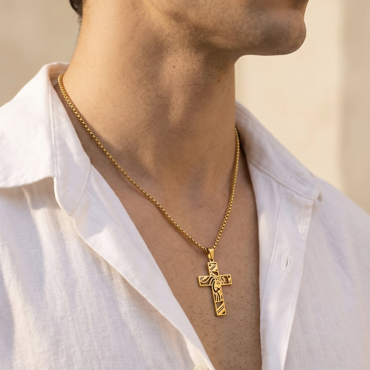 Side view of a man wearing a gold-tone sculpted cross necklace with an open white shirt.