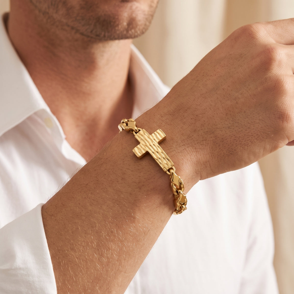 Gold-tone textured cross link bracelet worn on a man's wrist with a white button-up shirt visible.