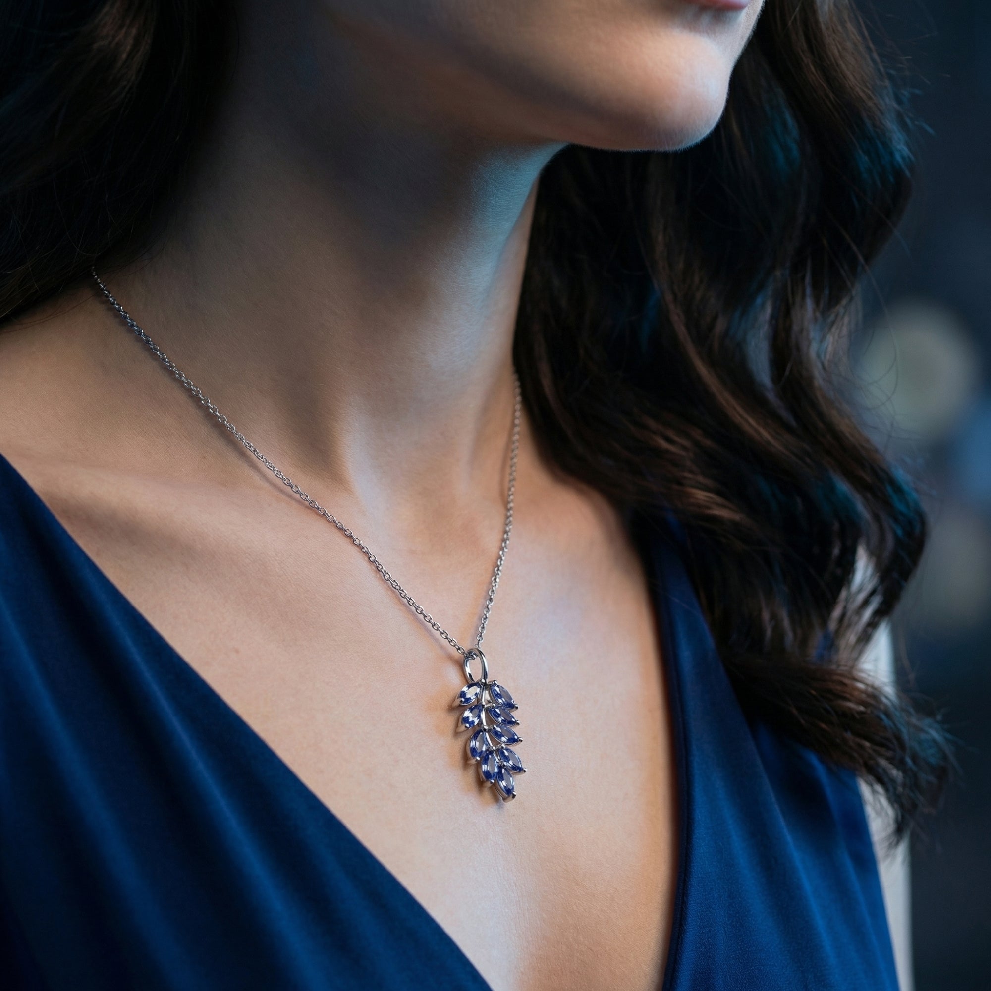 Front view of a model wearing the marquise tanzanite cluster necklace in white gold with a blue dress.