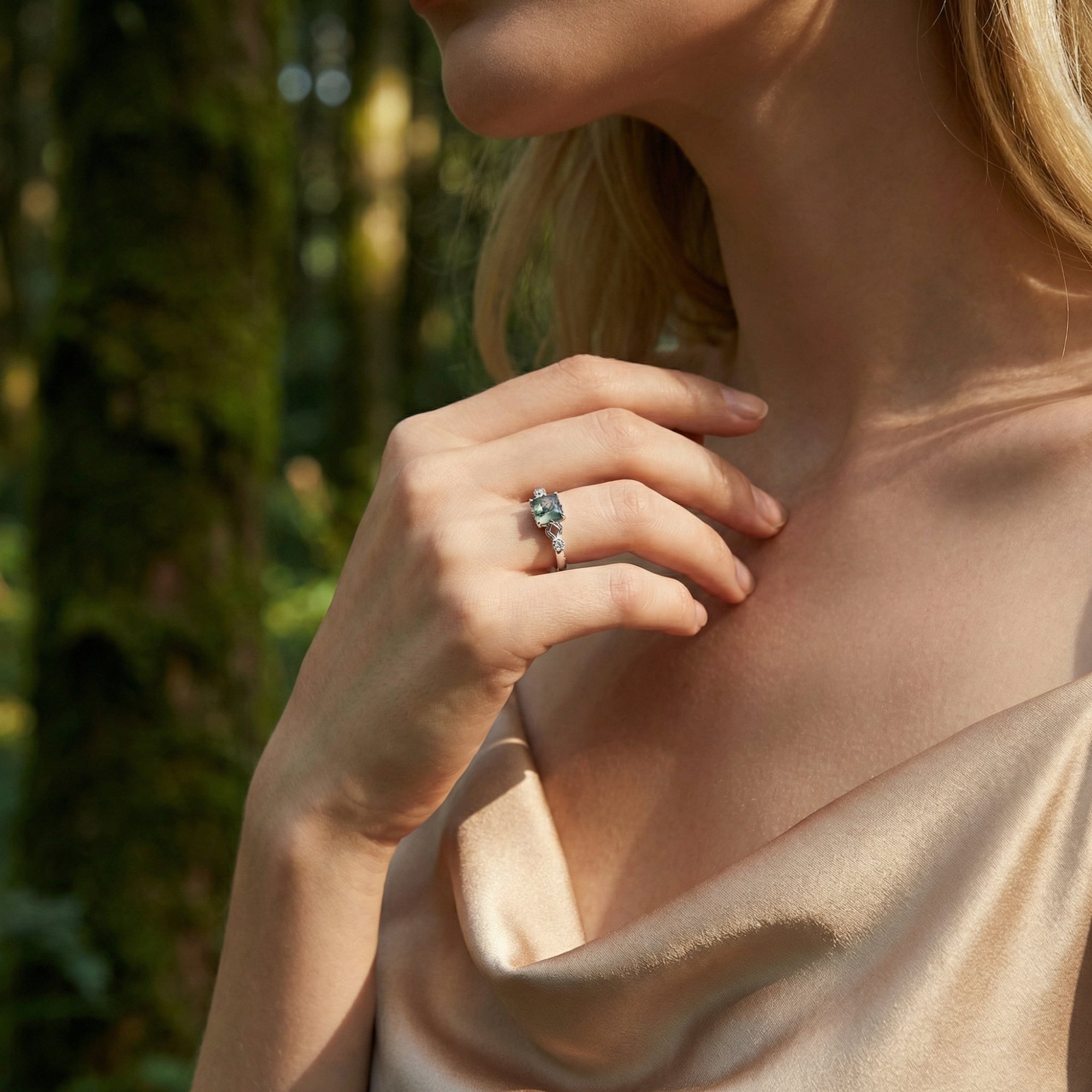 Elegant view of the cushion cut moss agate sterling silver ring worn by a model in a natural forest setting.