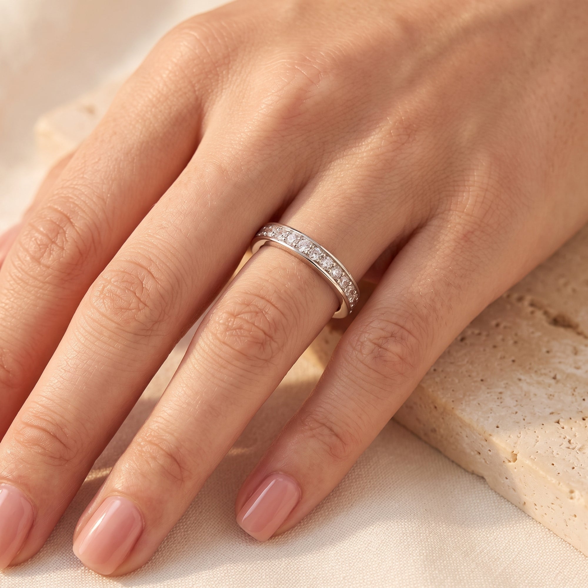 Top view of silver cubic zirconia eternity ring on a woman's hand.