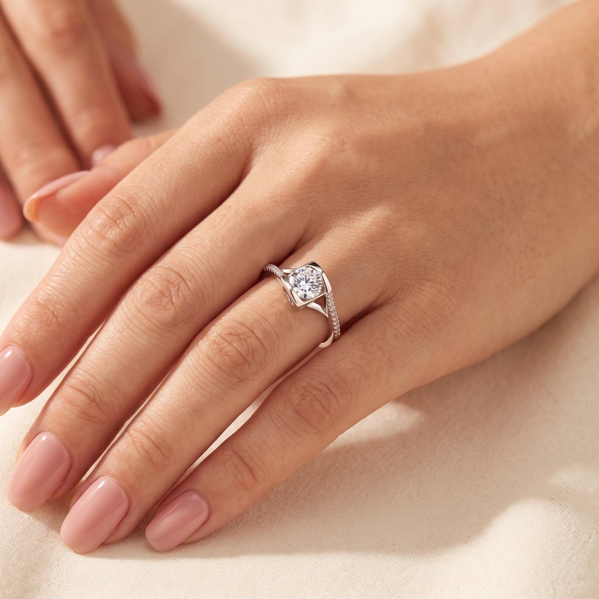 Sterling silver round-cut solitaire promise ring shown on a model's hand against a soft fabric background.