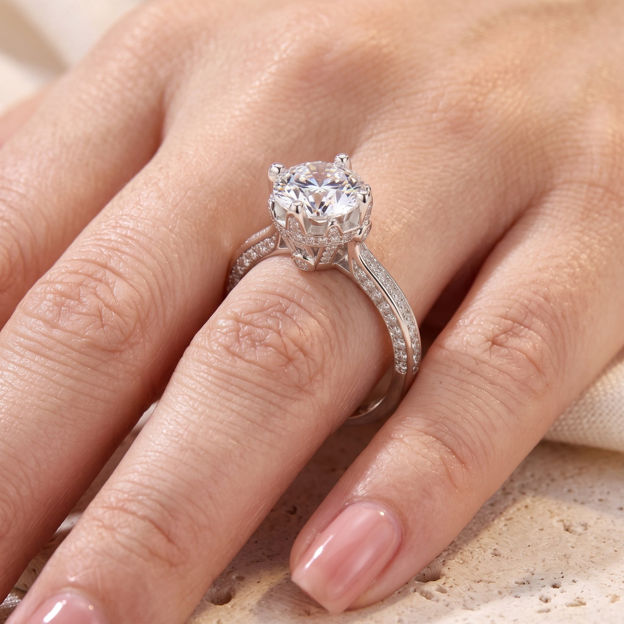 Close-up of the 8mm brilliant stone and crown setting on a sterling silver ring worn on a finger.