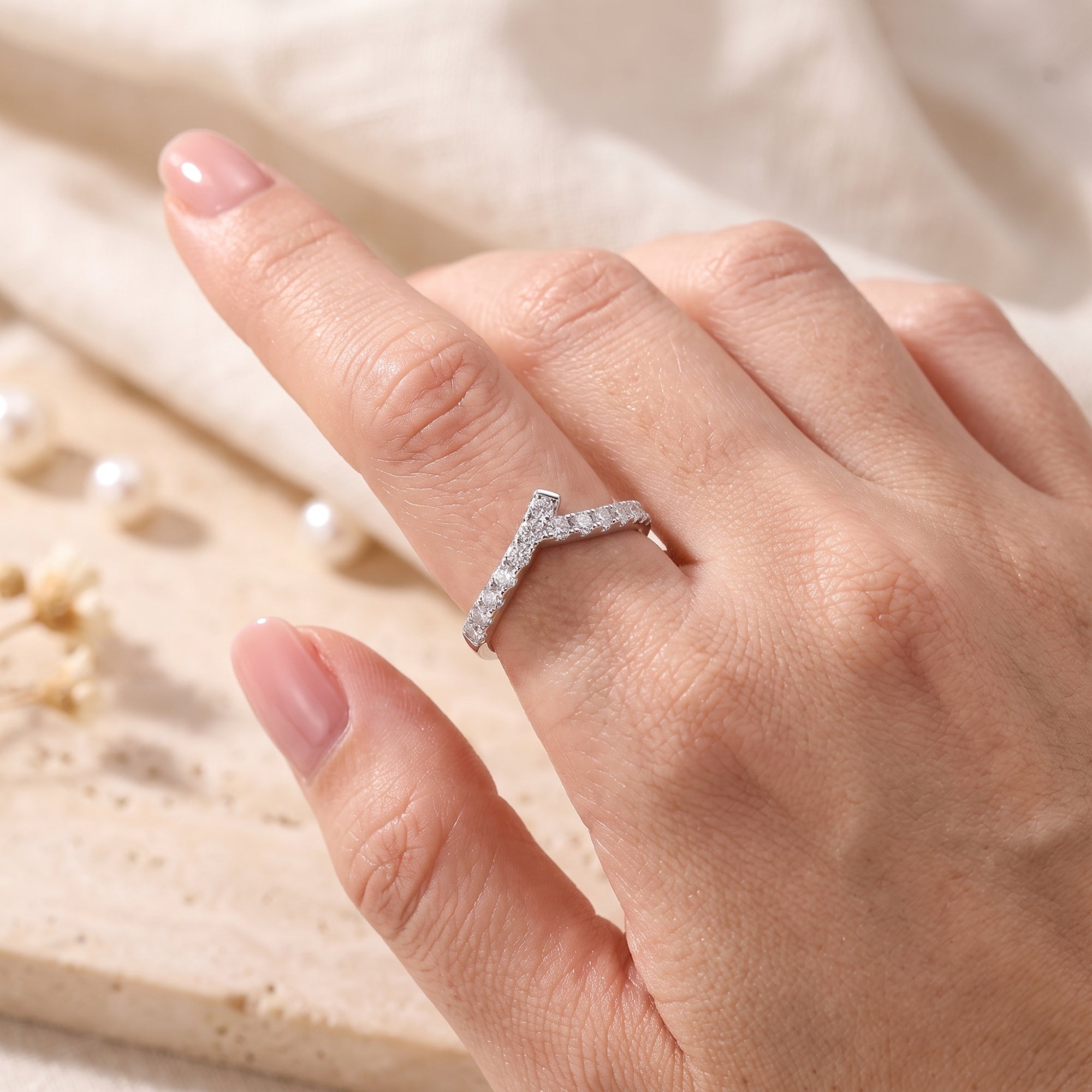Angled view of S925 silver asymmetric chevron ring with pave stones on finger.