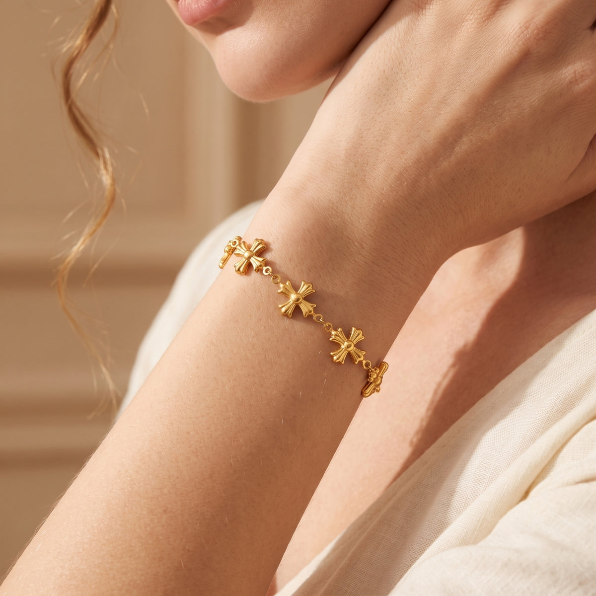 Close-up of a model wearing the gold cross bracelet, with her wrist raised near her face.