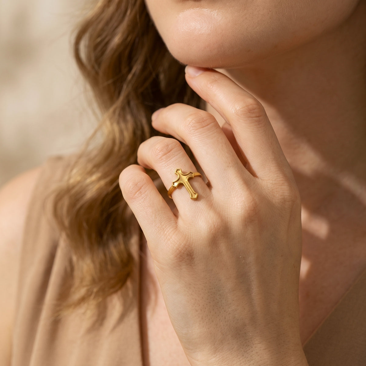 Portrait view of a woman wearing the gold-tone cross ring with her hand beneath her chin.