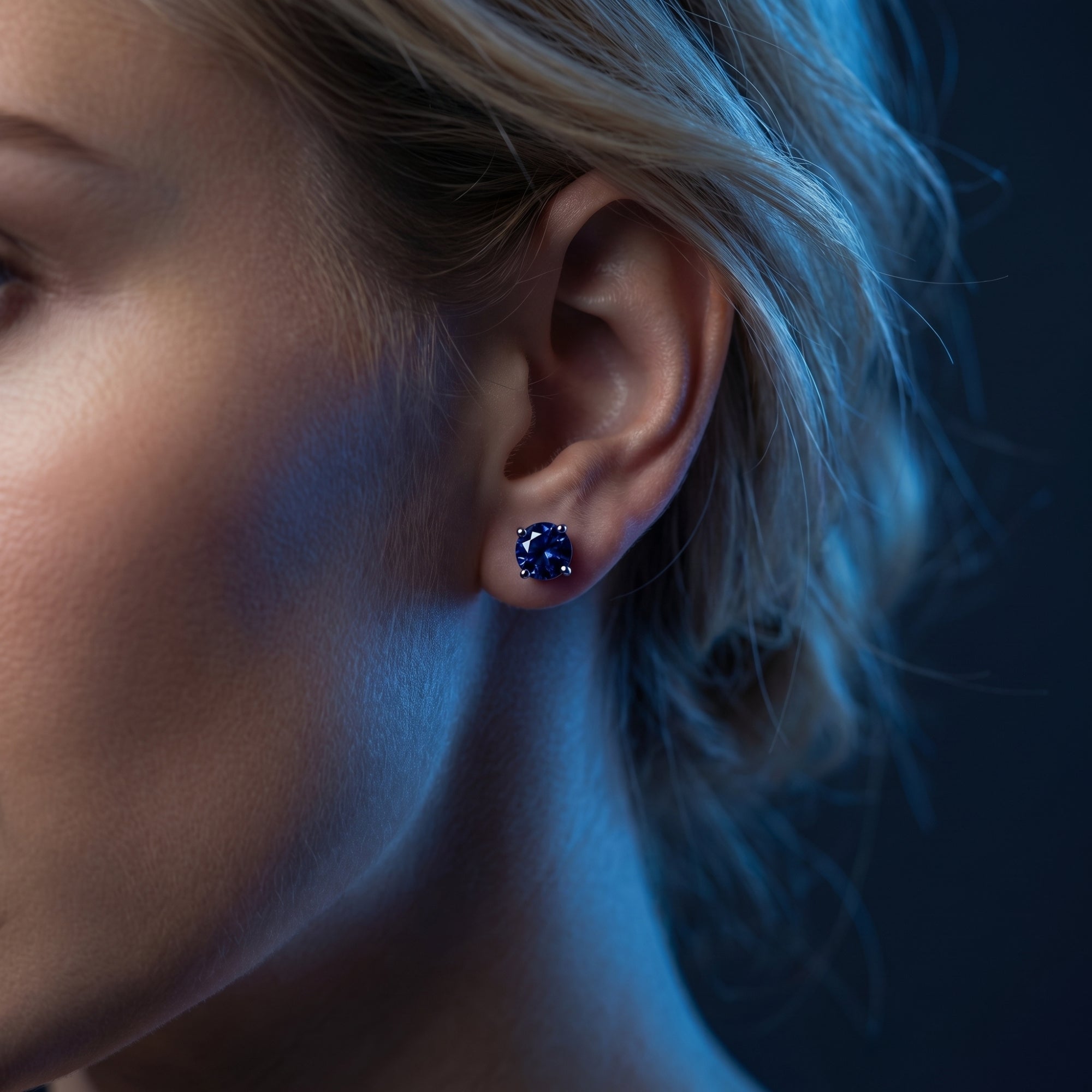 Side profile of a model wearing a deep blue round tanzanite stud earring in 18K white gold.
