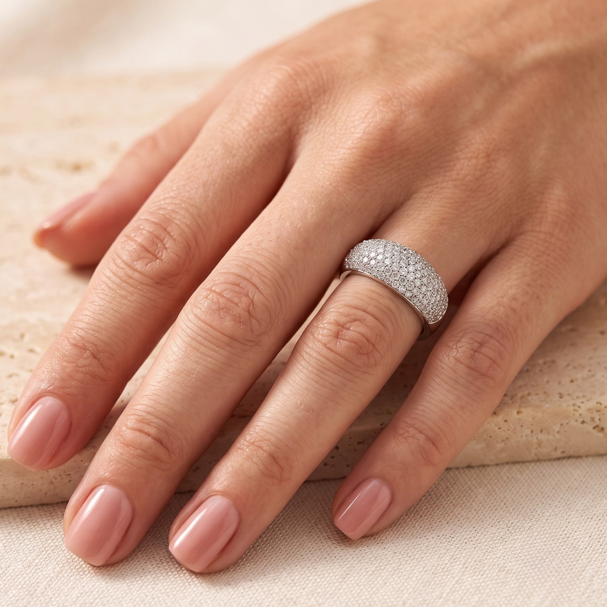 Wide silver dome ring with CZ pave on a finger for scale and fit.