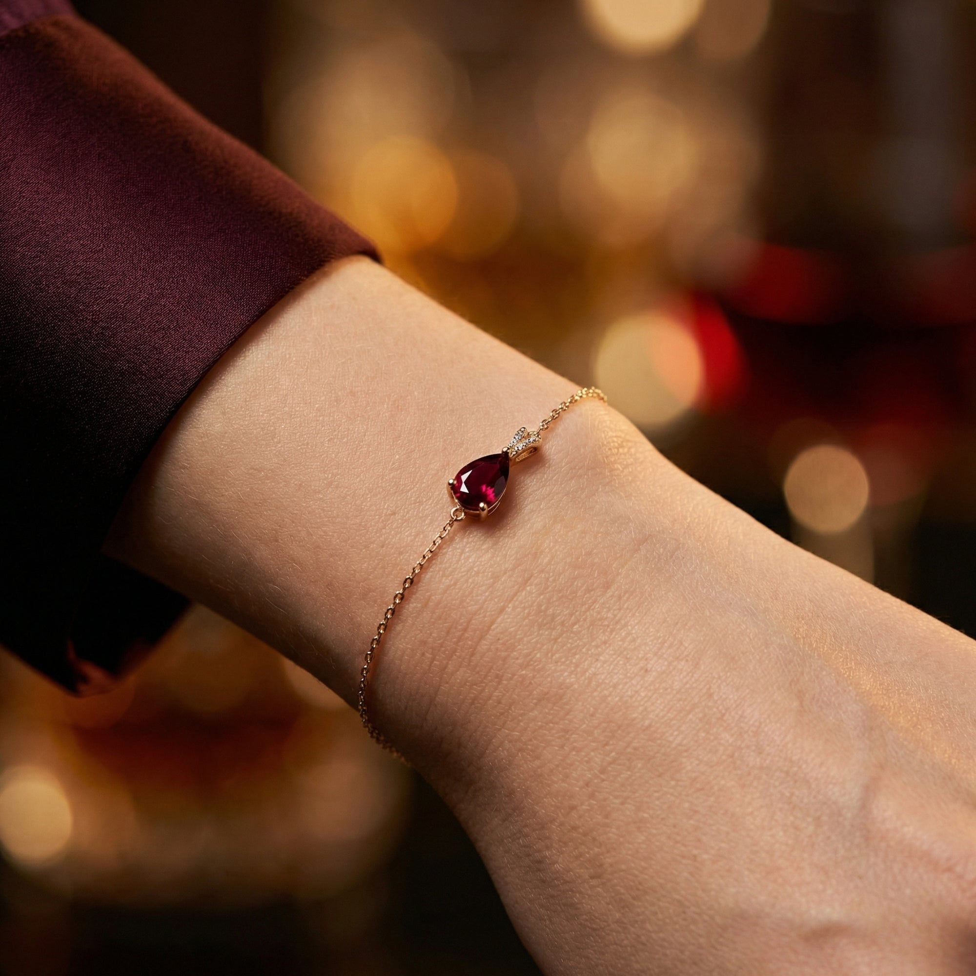 Close-up of the 18K rose gold Maelle bracelet featuring a pear cut garnet on a model's wrist.