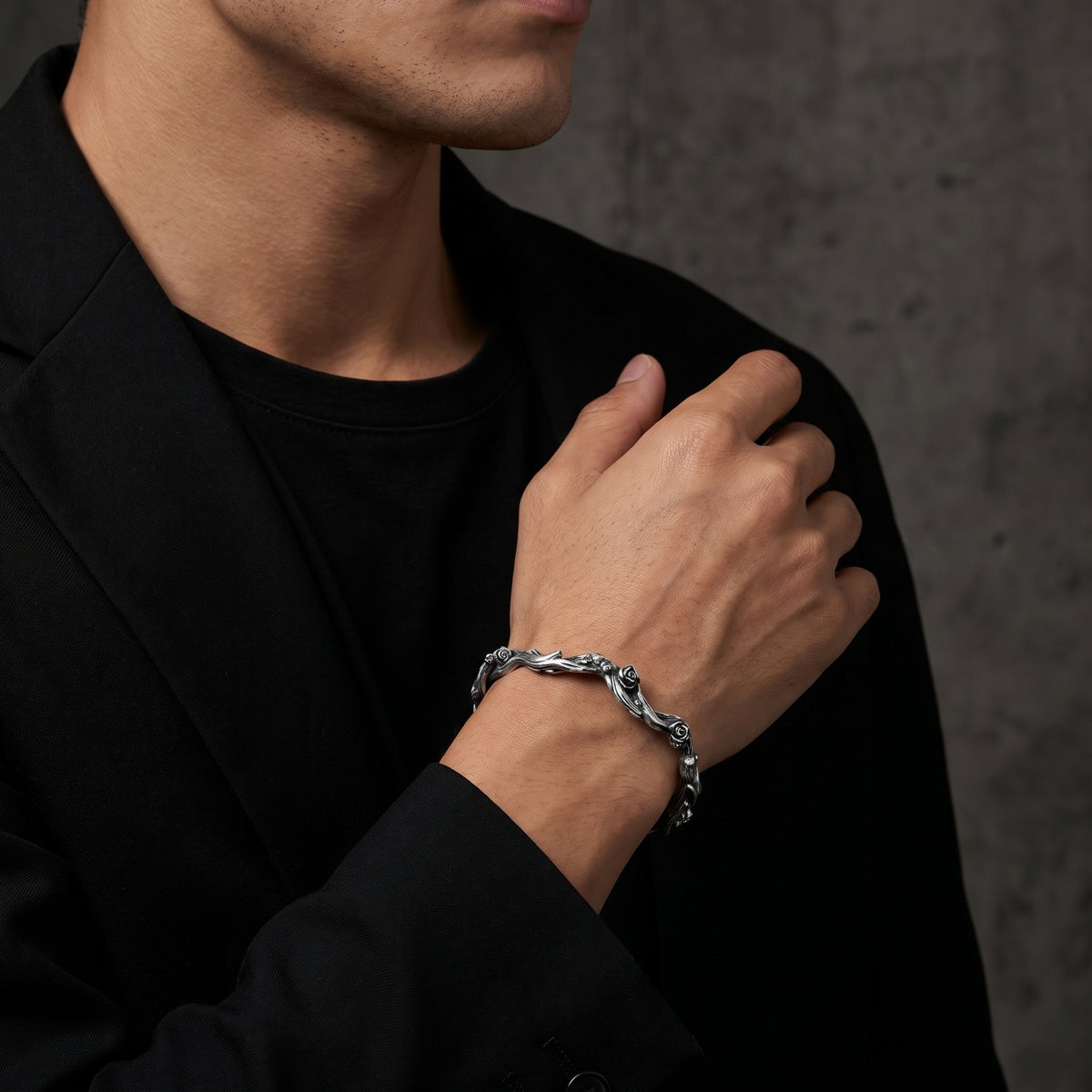 Silver rose vine cuff bracelet worn on a wrist over a black blazer and shirt.