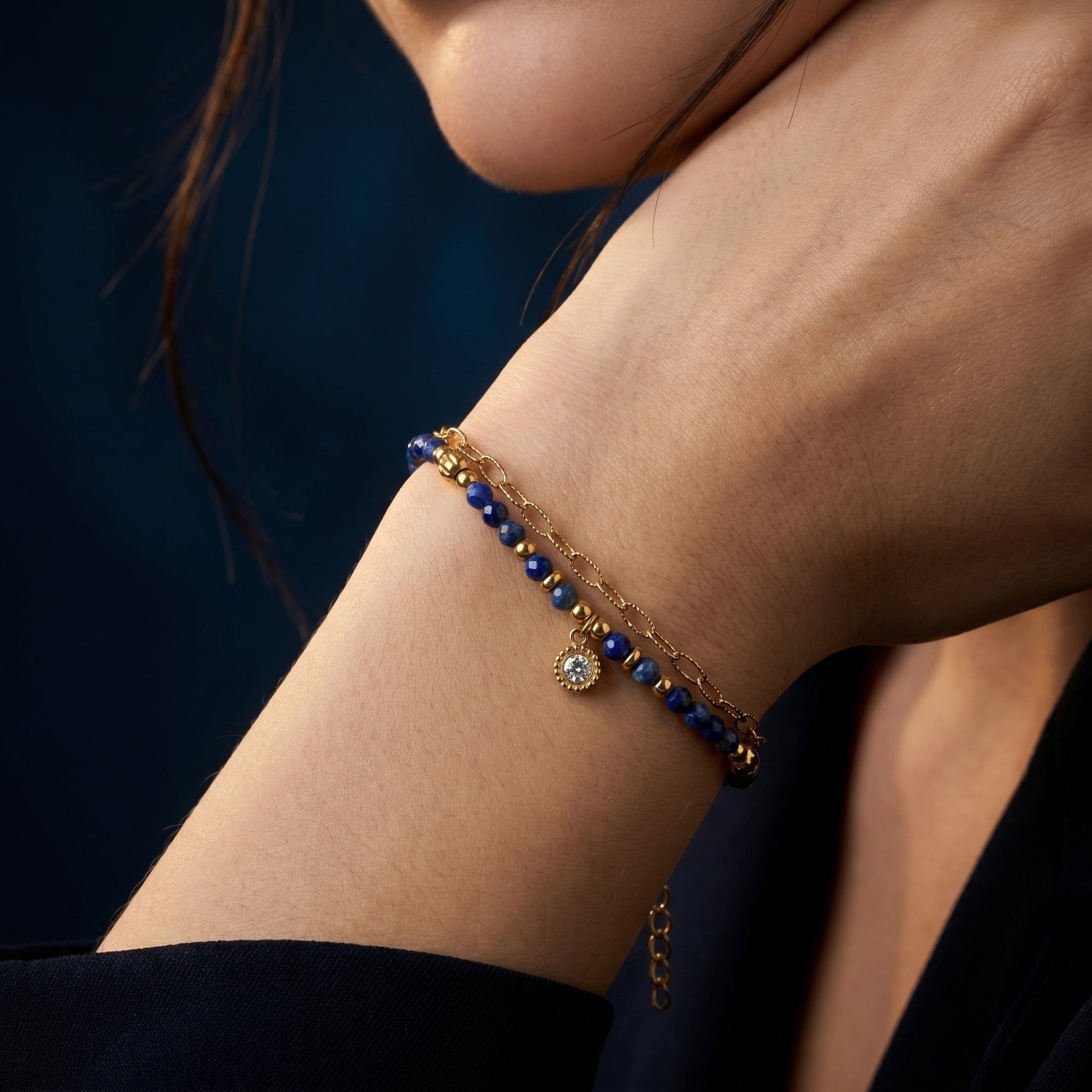 Detailed view of the 3mm natural lapis lazuli beads and gold charm worn on a model's wrist.