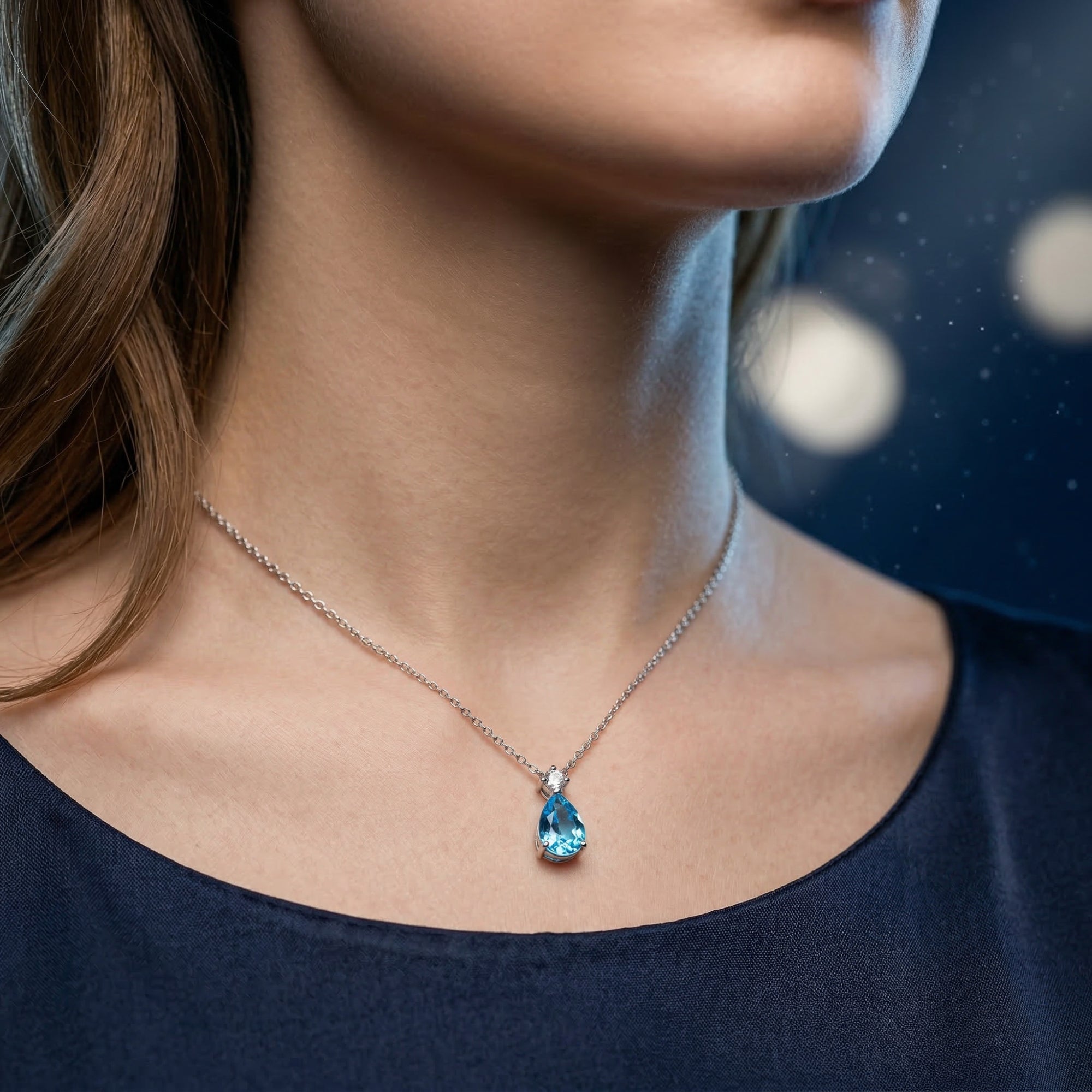 A woman wearing the pear cut natural Swiss Blue topaz necklace in sterling silver.