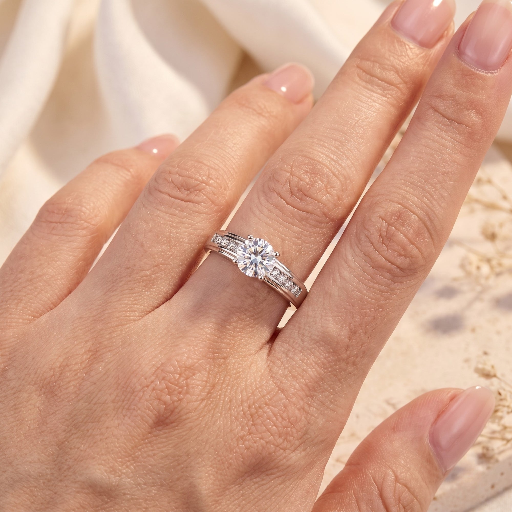 Top view of the silver promise ring with channel-set side stones and round center stone on a hand.